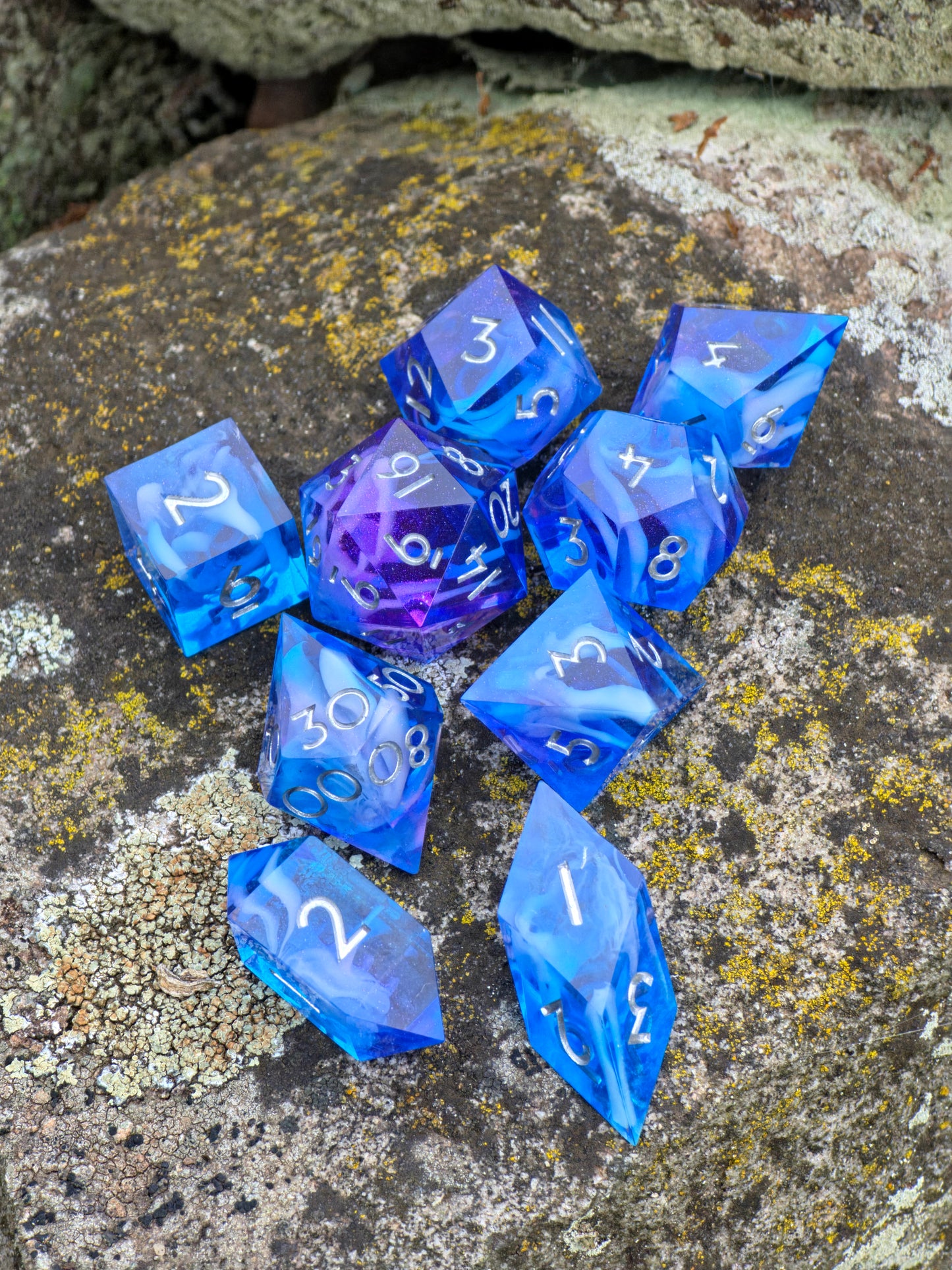 Komplettes 9-teiliges Cloud Nebula Resin Würfelset in Blau und Lila auf Naturstein, inspiriert von der Galaxie.