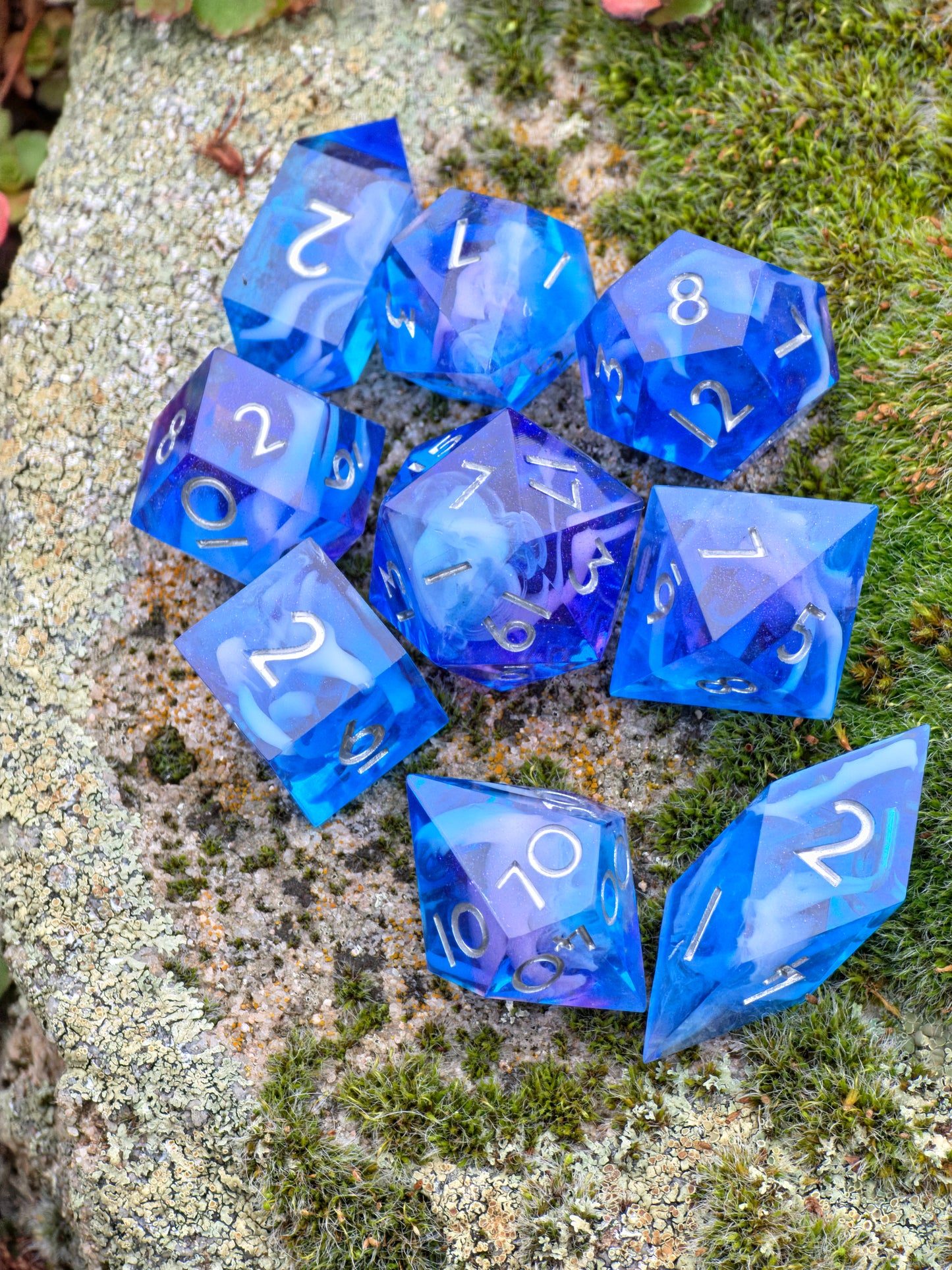 Makroaufnahme eines blauen polyedrischen Würfelsets aus Resin mit lila Schimmer und klarer Struktur.