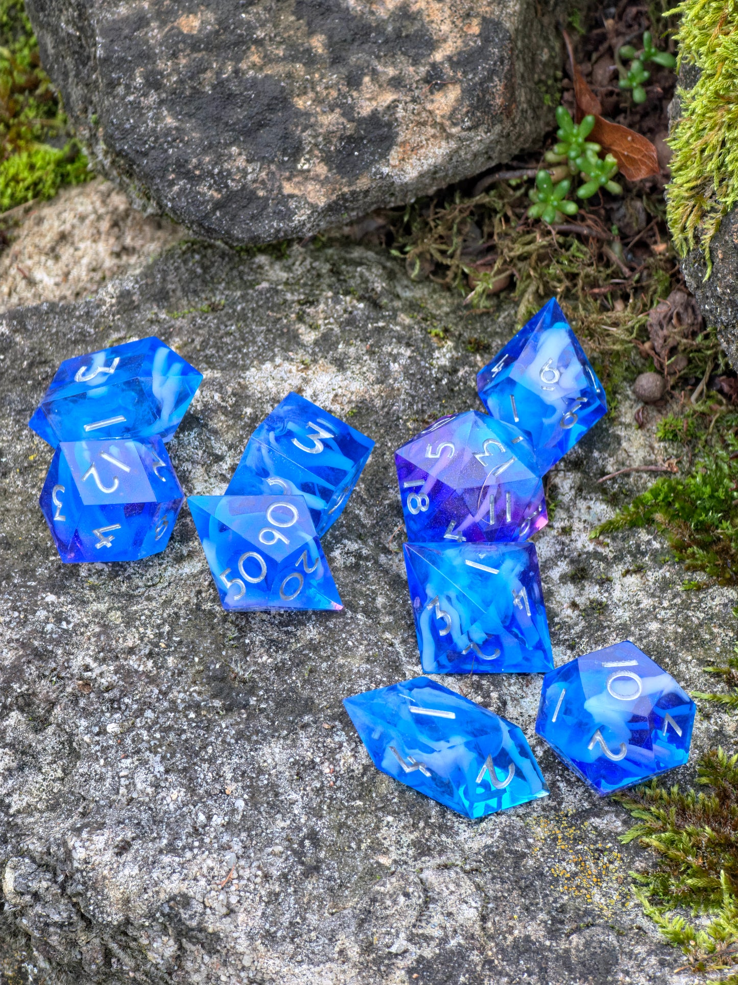 Detaillierte Ansicht der Cloud Nebula Dice in Blau-Lila mit weißen Zahlen auf einem Felsen.