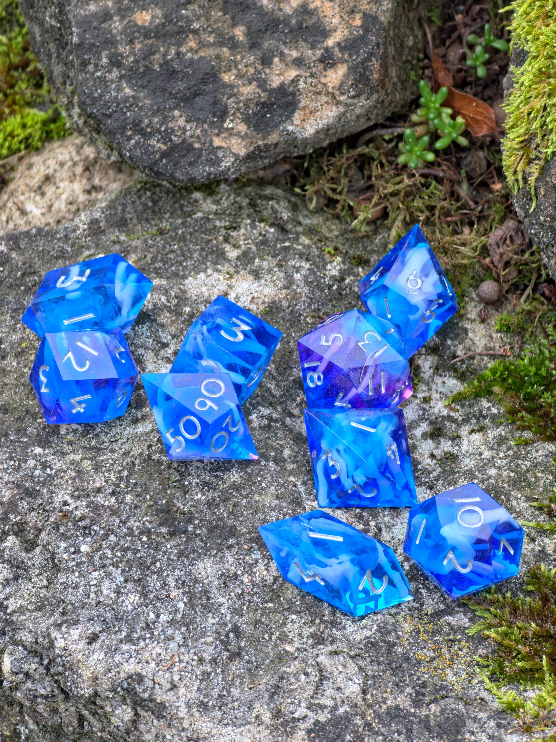 Detaillierte Ansicht der Cloud Nebula Dice in Blau-Lila mit weißen Zahlen auf einem Felsen.