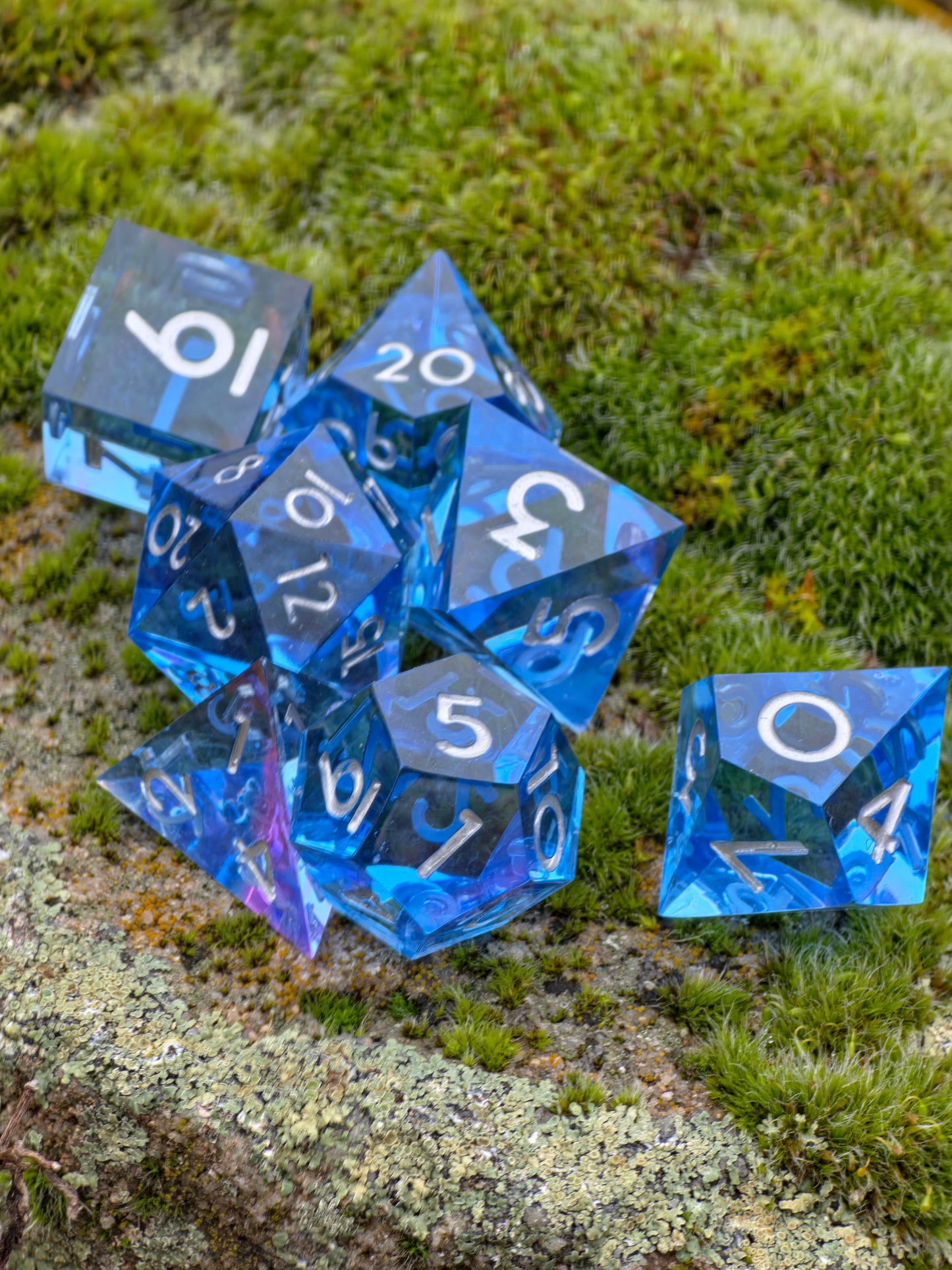 Polyedrisches „Abyss of the Sapphire Tide“ Würfelset mit allen Würfelformen, einheitliches klares Blau.  
Polyhedral “Abyss of the Sapphire Tide” dice set with all dice shapes in consistent clear blue tones.