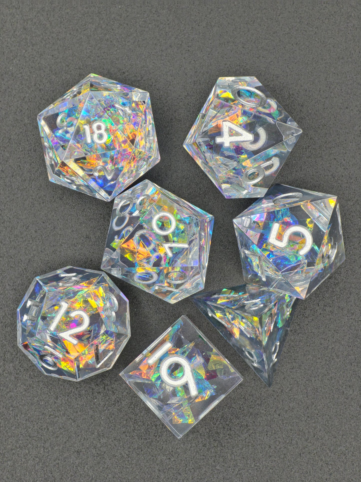 Handaufnahme des „Aether Shards“ Sets mit irisierenden holografischen Splittern und silbernen Zahlen. 
Hand shot of the “Aether Shards” set with iridescent holographic shards and silver numbers.