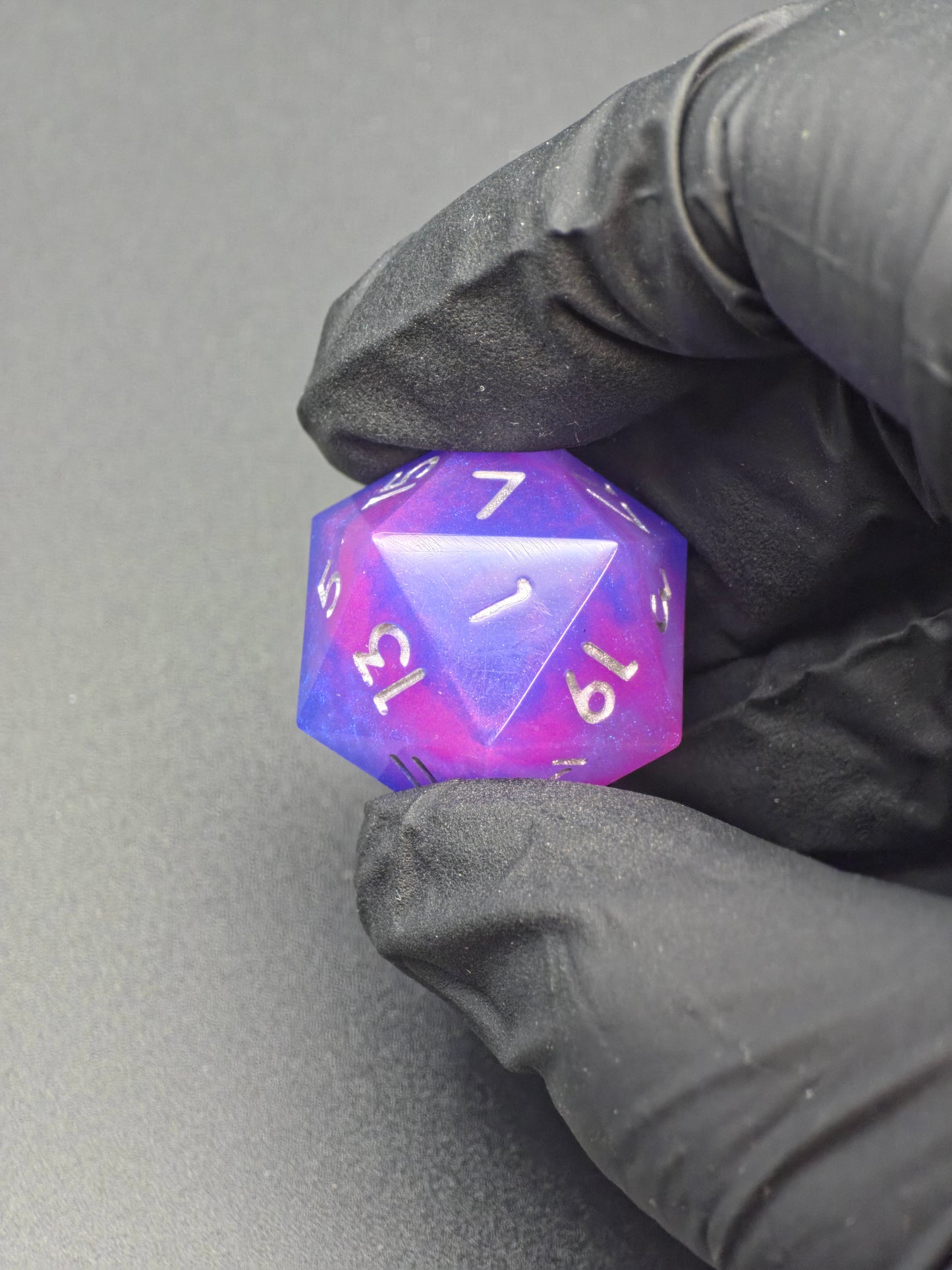 Galerieansicht des „Aetherfall D20“, handgemachter lila-blauer Resinwürfel mit silberner Beschriftung aus verschiedenen Perspektiven. 
Gallery view of the “Aetherfall D20”, handmade purple-blue resin die with silver numbering from multiple angles.