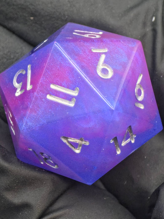 Aetherfall D20 – handgemachter lila-blauer Resinwürfel mit silbernen Zahlen im Hero-Shot. 
Aetherfall D20 – handmade purple-blue resin D20 with silver numbers in a hero shot.