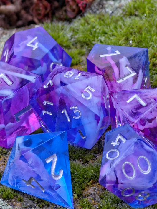 Amethyst Tide handgemachtes DnD Würfelset aus Resin mit blau-violettem Nebula- und Cloud-Effekt.  
Amethyst Tide handmade DnD dice set made of resin with blue and violet nebula and cloud effect.