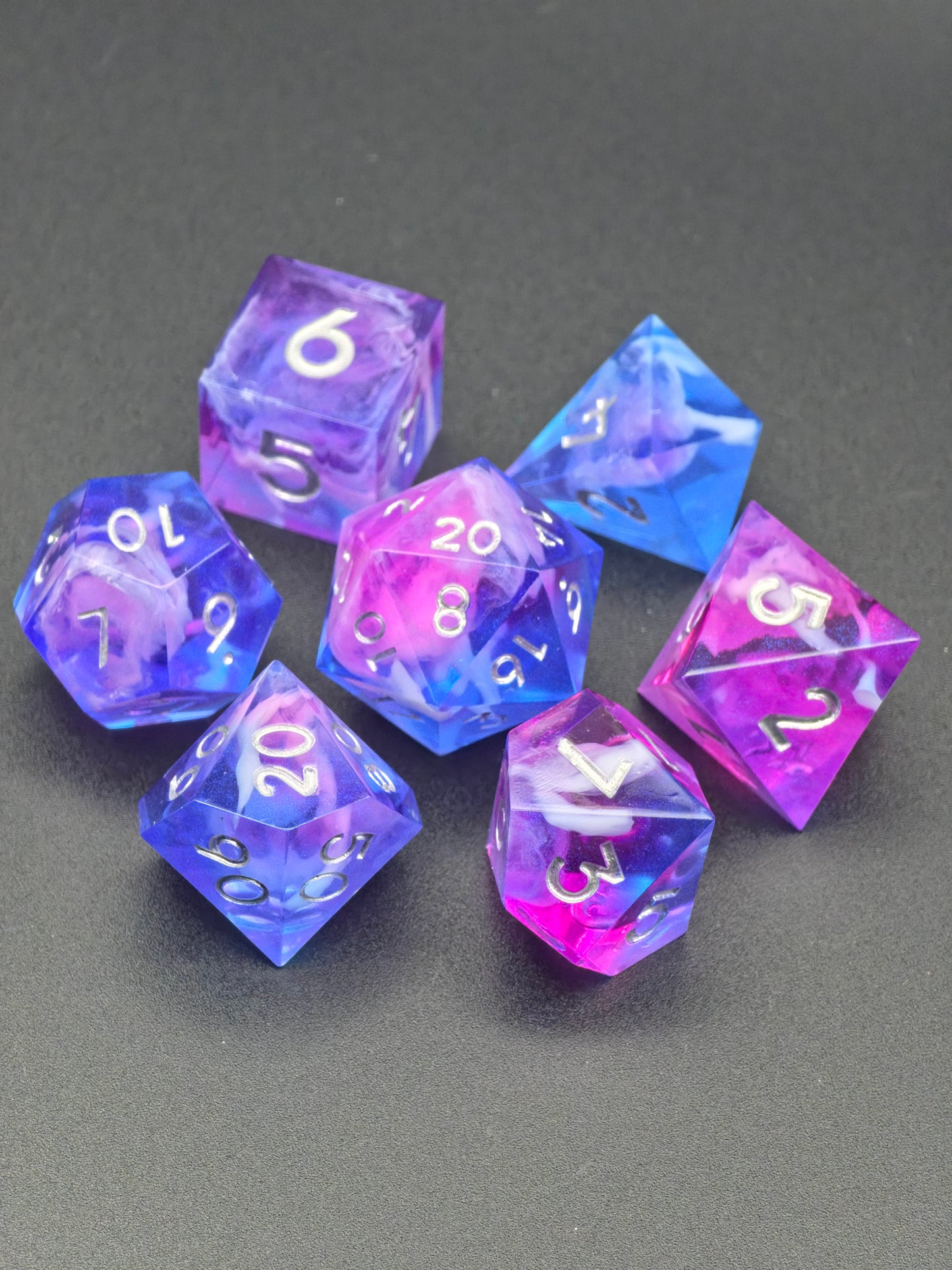 Detailansicht der weißen Zahlen und der blau-violetten Resin-Strukturen im Amethyst Tide Würfelset.  
Close-up view of white numbers and blue-violet resin structures in the Amethyst Tide dice set.