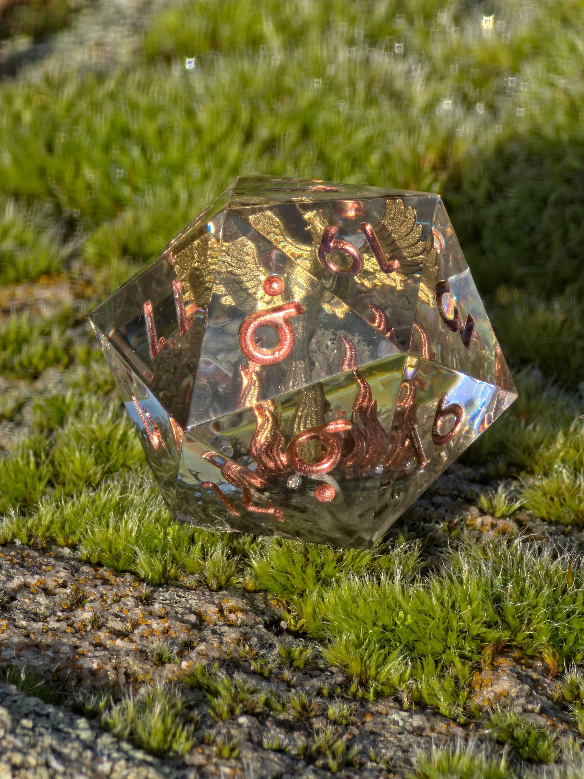 Aschekrone goldener Phönix D20 in Bewegung zur Darstellung von Lichtreflexionen im Resin.  
Aschekrone golden phoenix D20 in motion showing resin depth and light reflections.