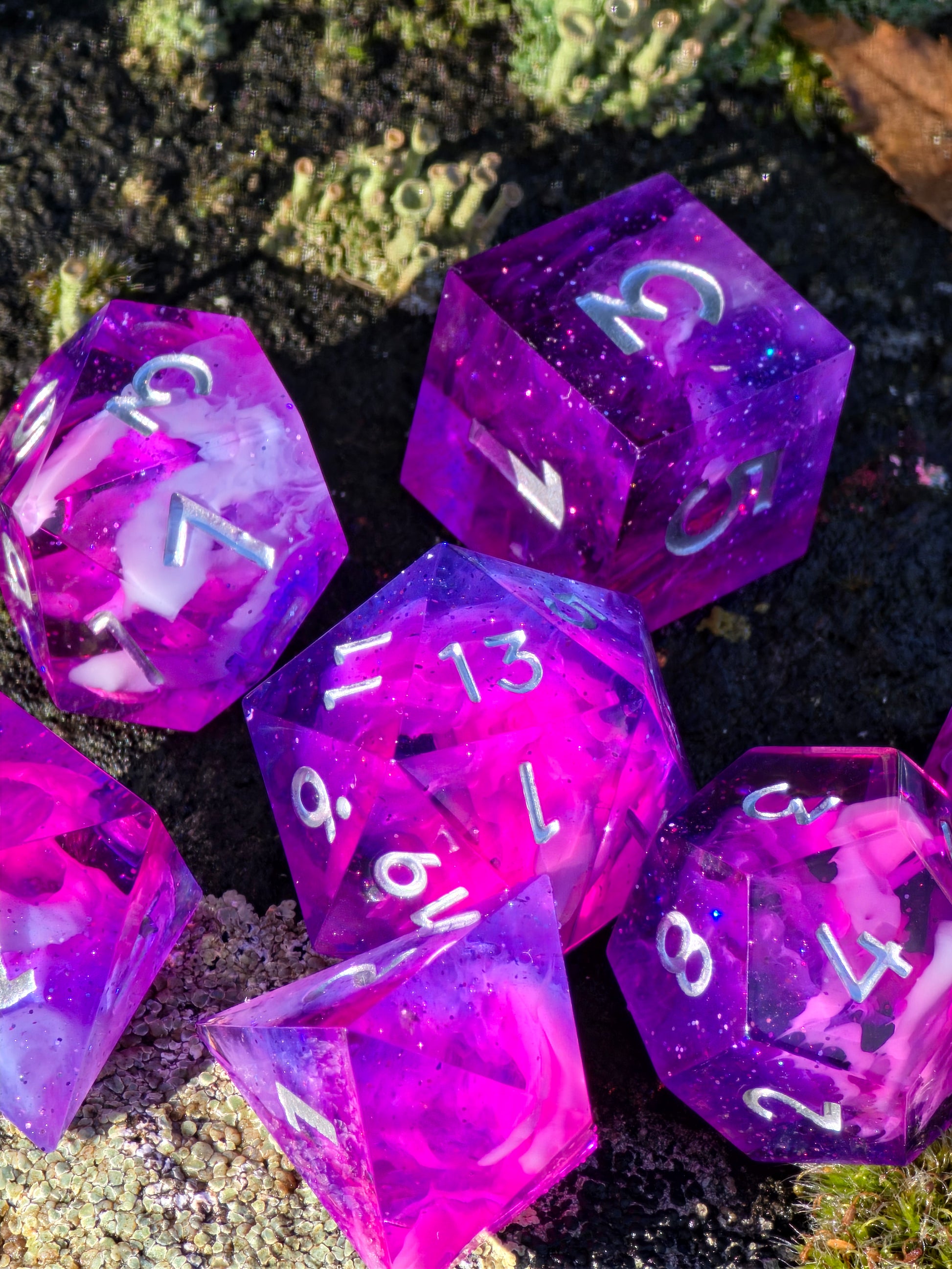 Detailaufnahme des „Astral Bloom Nebula“ Würfelsets – schimmernde Pigmente, weiche Cloud-Strukturen und klare Kanten.  
Close-up of the “Astral Bloom Nebula” dice set – shimmering pigments, soft cloud structures, and sharp edges.