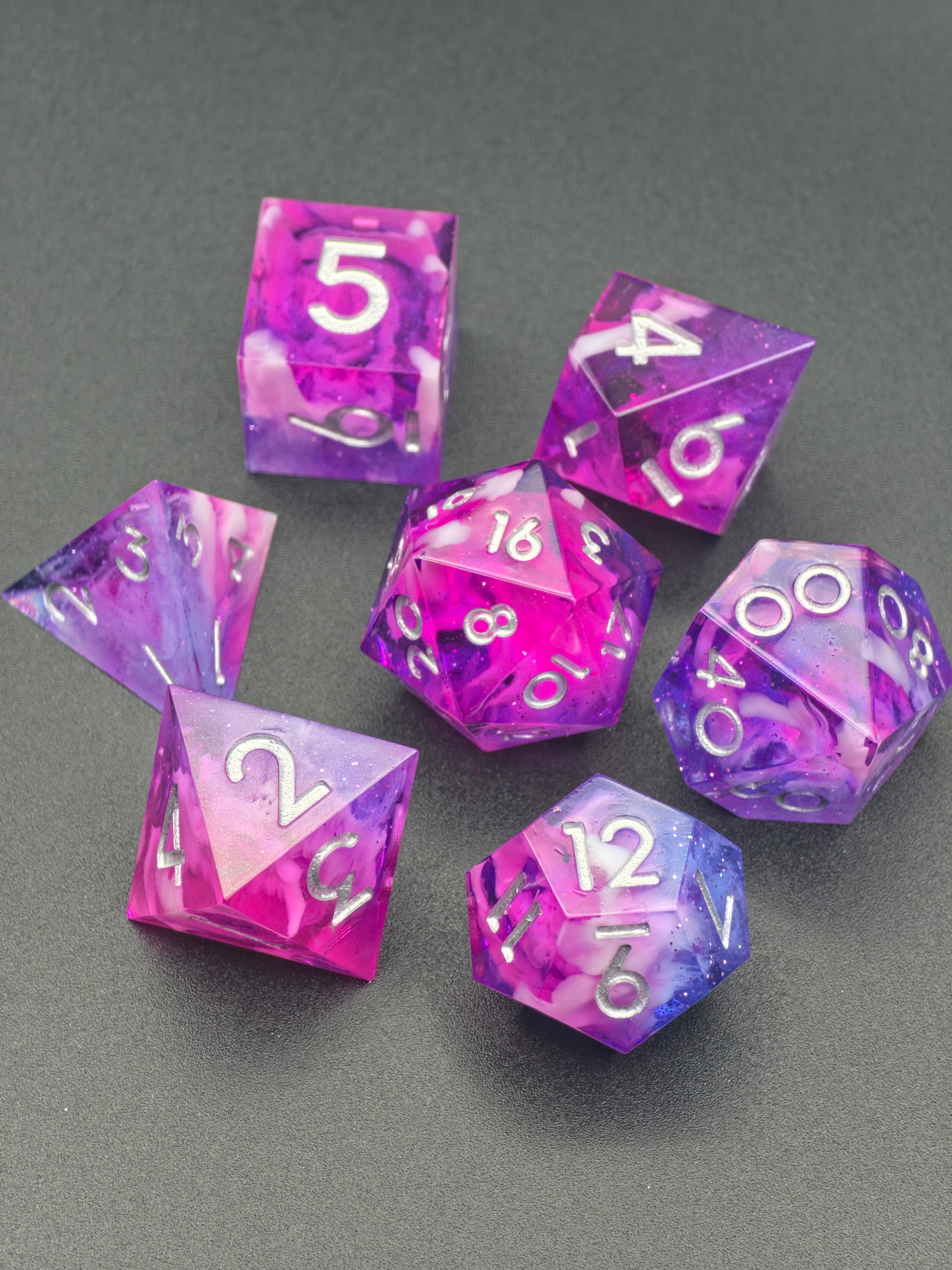 Astral Orchard“ – 7-teiliges polydedrisches Würfelset von oben, transparente Schichten mit silberner Beschriftung.  
Astral Orchard” – 7-piece polyhedral dice set top view, transparent layers with silver numbering.