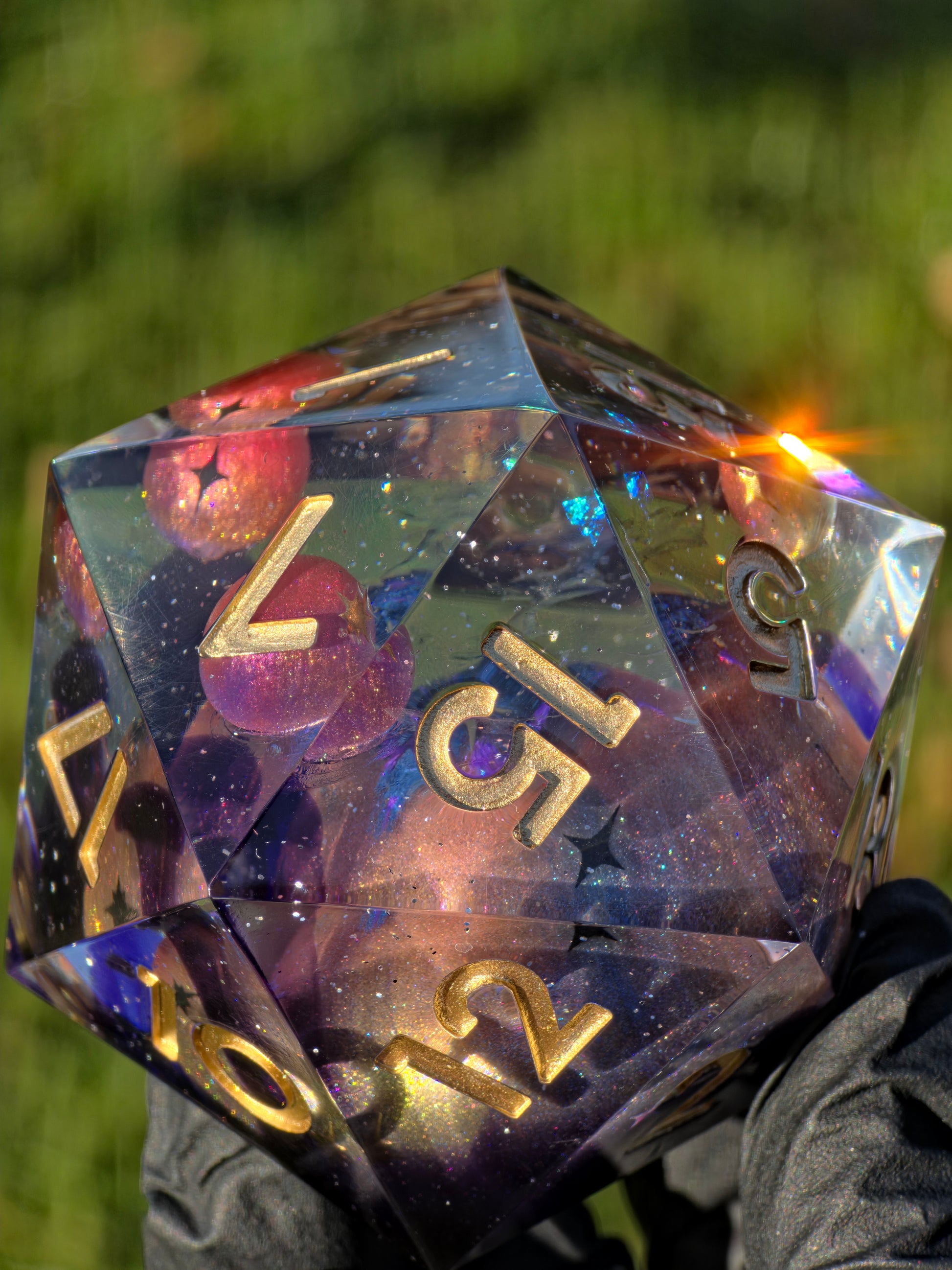 „Celestial Sphere“ XXL D20 – transparenter 55-mm Würfel mit vier Mini-Planeten und violett-goldenem Galaxy-Effekt.  
“Celestial Sphere” XXL D20 – transparent 55 mm die with four mini planets and a purple-gold galaxy effect.
