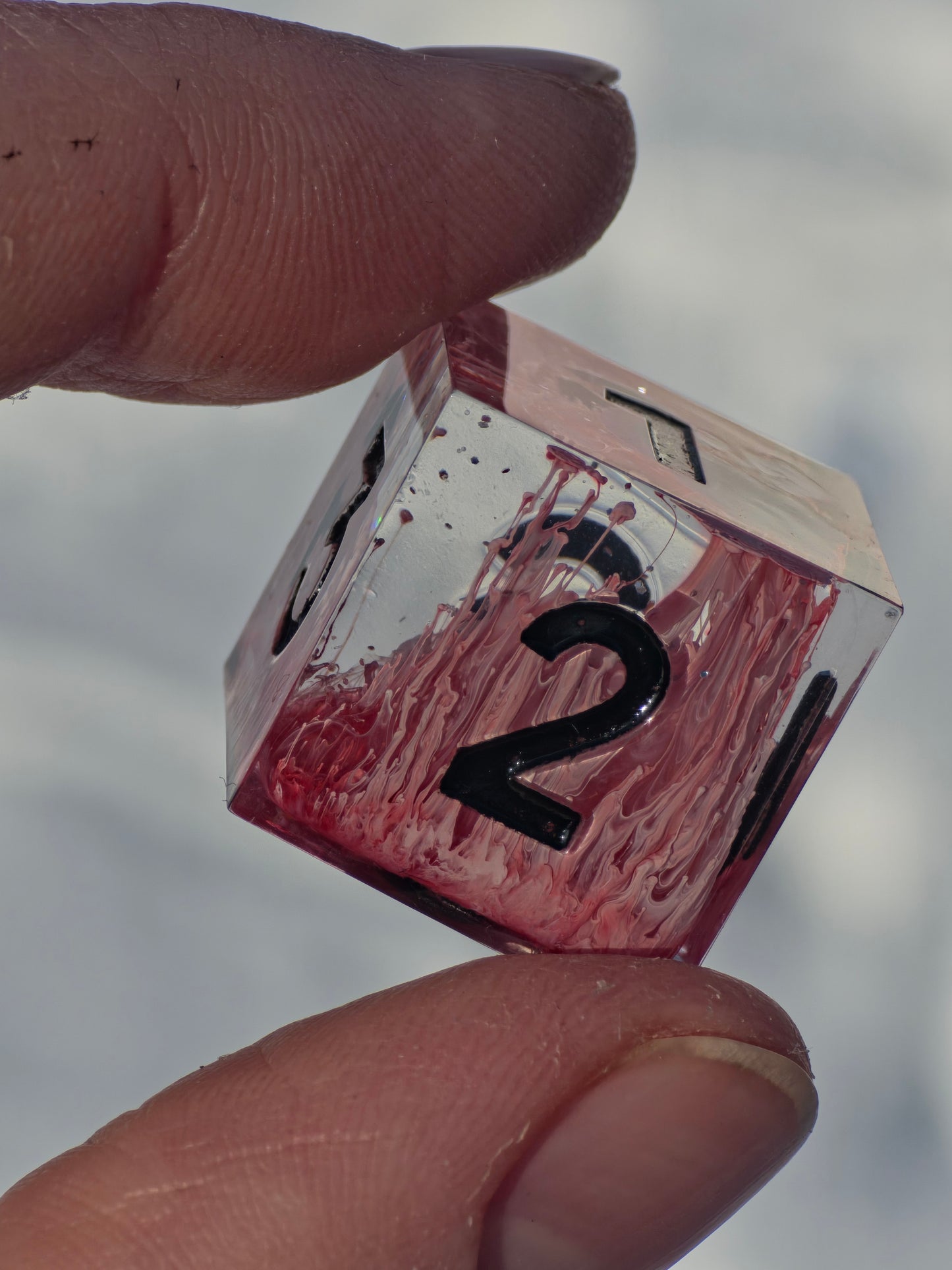 Detailaufnahme der Zahlen und Oberfläche des Crimson Bloom Resin Würfelsets.  
Close-up of the numbers and surface of the Crimson Bloom resin dice set.