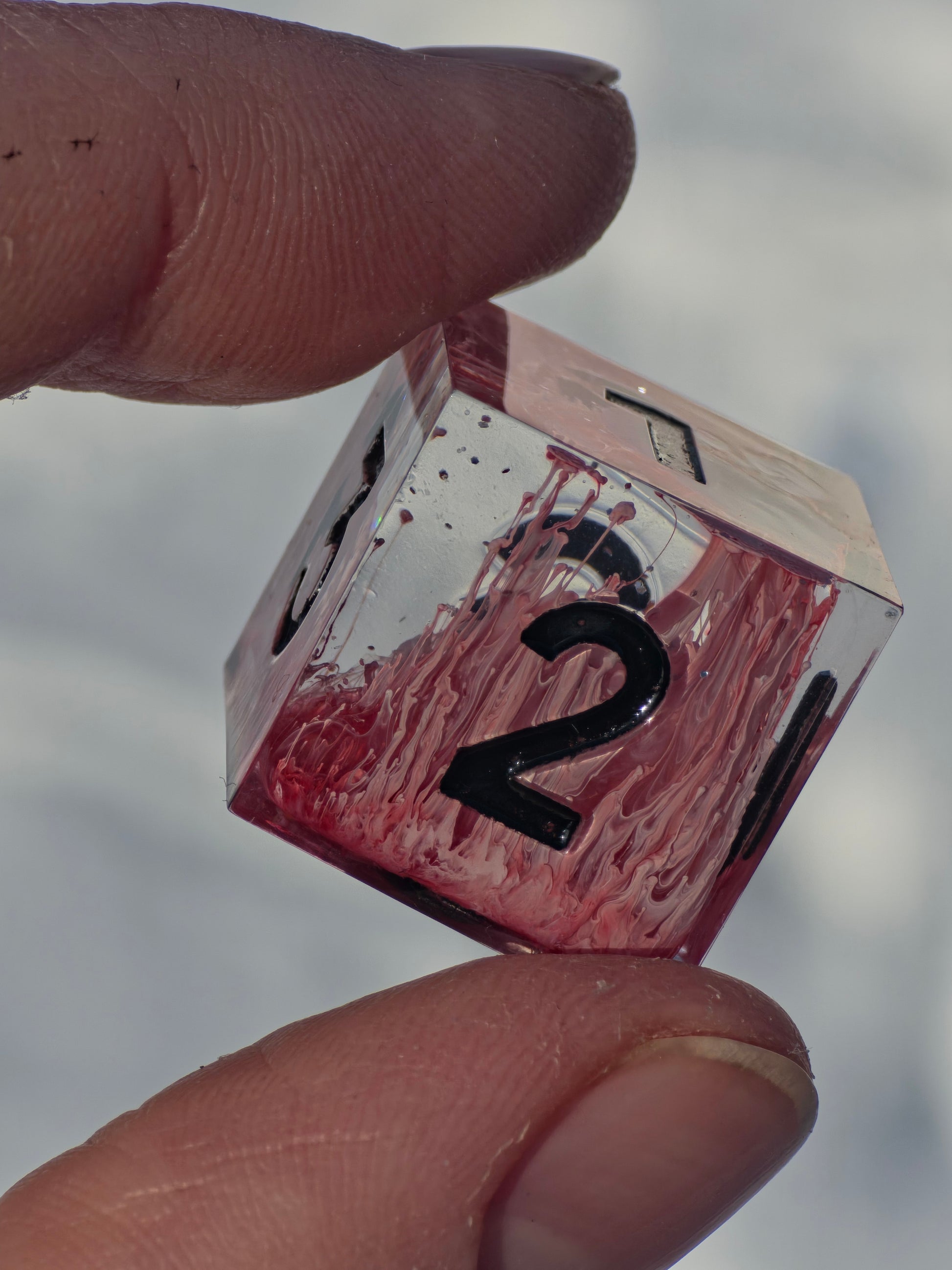 Detailaufnahme der Zahlen und Oberfläche des Crimson Bloom Resin Würfelsets.  
Close-up of the numbers and surface of the Crimson Bloom resin dice set.