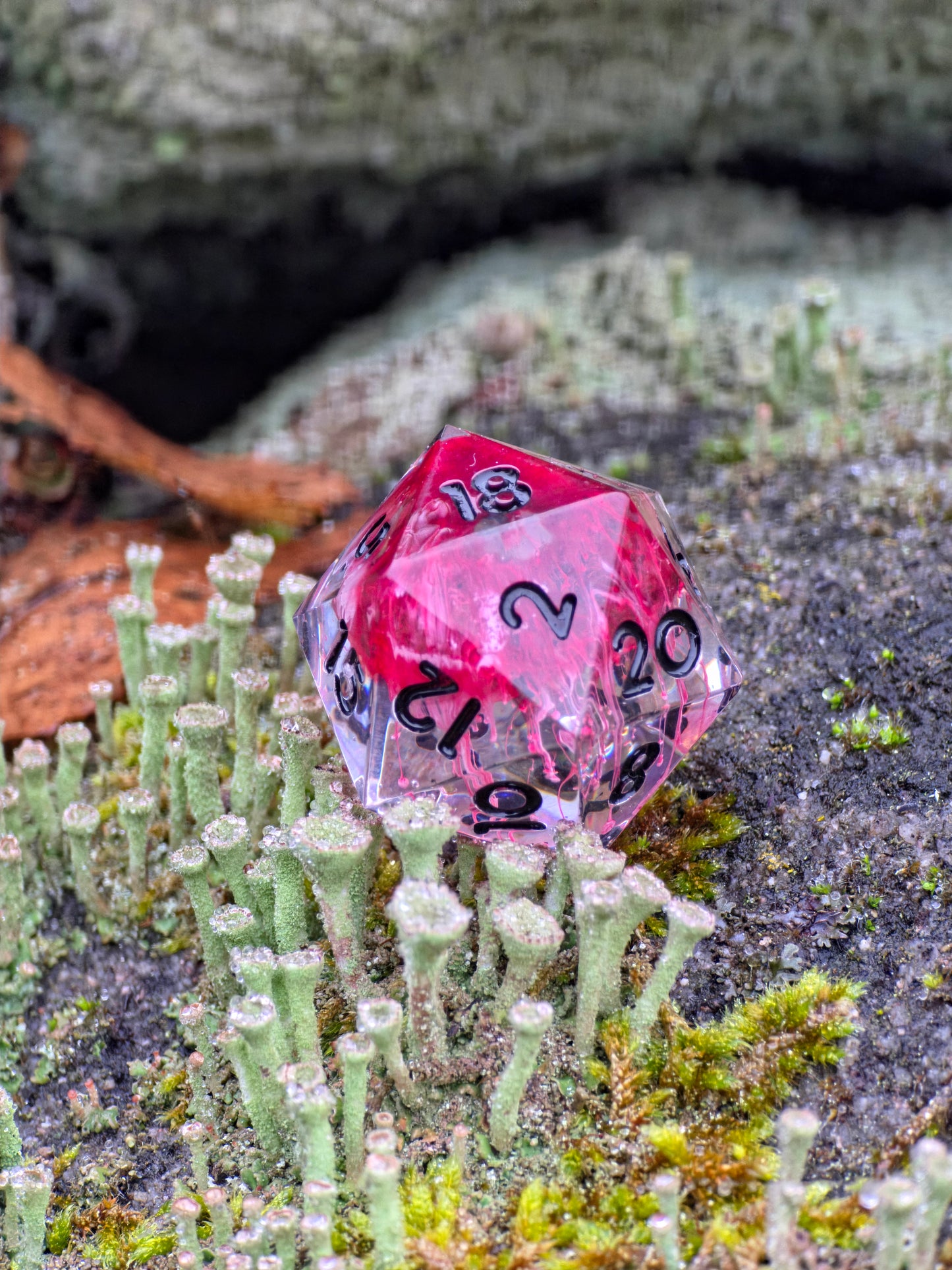 Einzelner Crimson Veins D20 Würfel in der Hand gehalten zur Darstellung von Größe und Details.  
Single Crimson Veins D20 dice held in hand to show size and fine details.