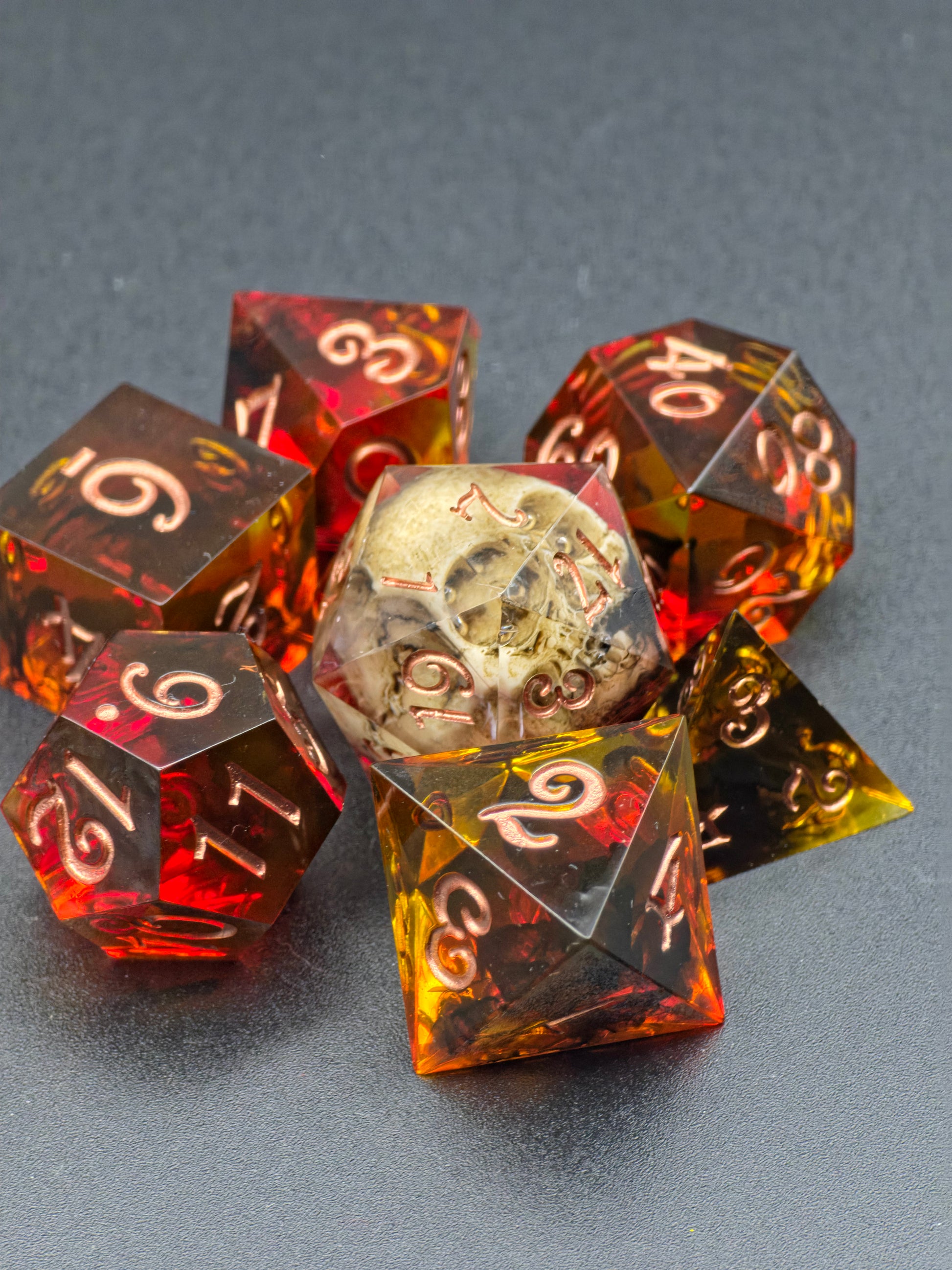 Detailaufnahme des D20 mit Schädel im „Ember Relic“ Würfelset, dunkle Fantasy-Optik in warmem Bernstein.  
Close-up of the skull D20 in the “Ember Relic” dice set, dark fantasy aesthetic in warm amber tones.