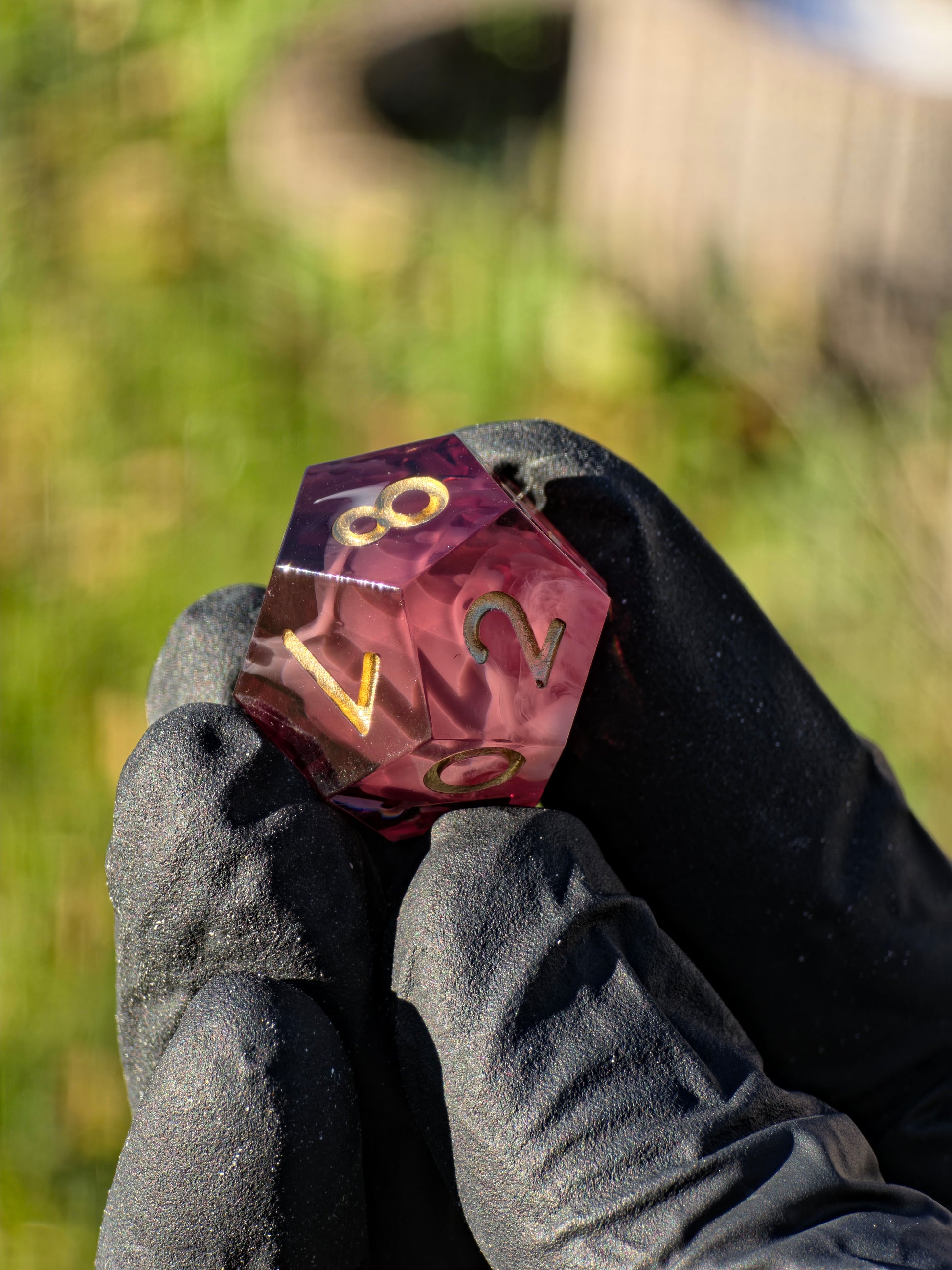 „Espresso Cream Nebula“ Würfel in der Hand – bordeauxfarbene Tiefe und goldener Nebeleffekt.  
“Espresso Cream Nebula” dice in hand – deep bordeaux resin with a golden cloud effect.