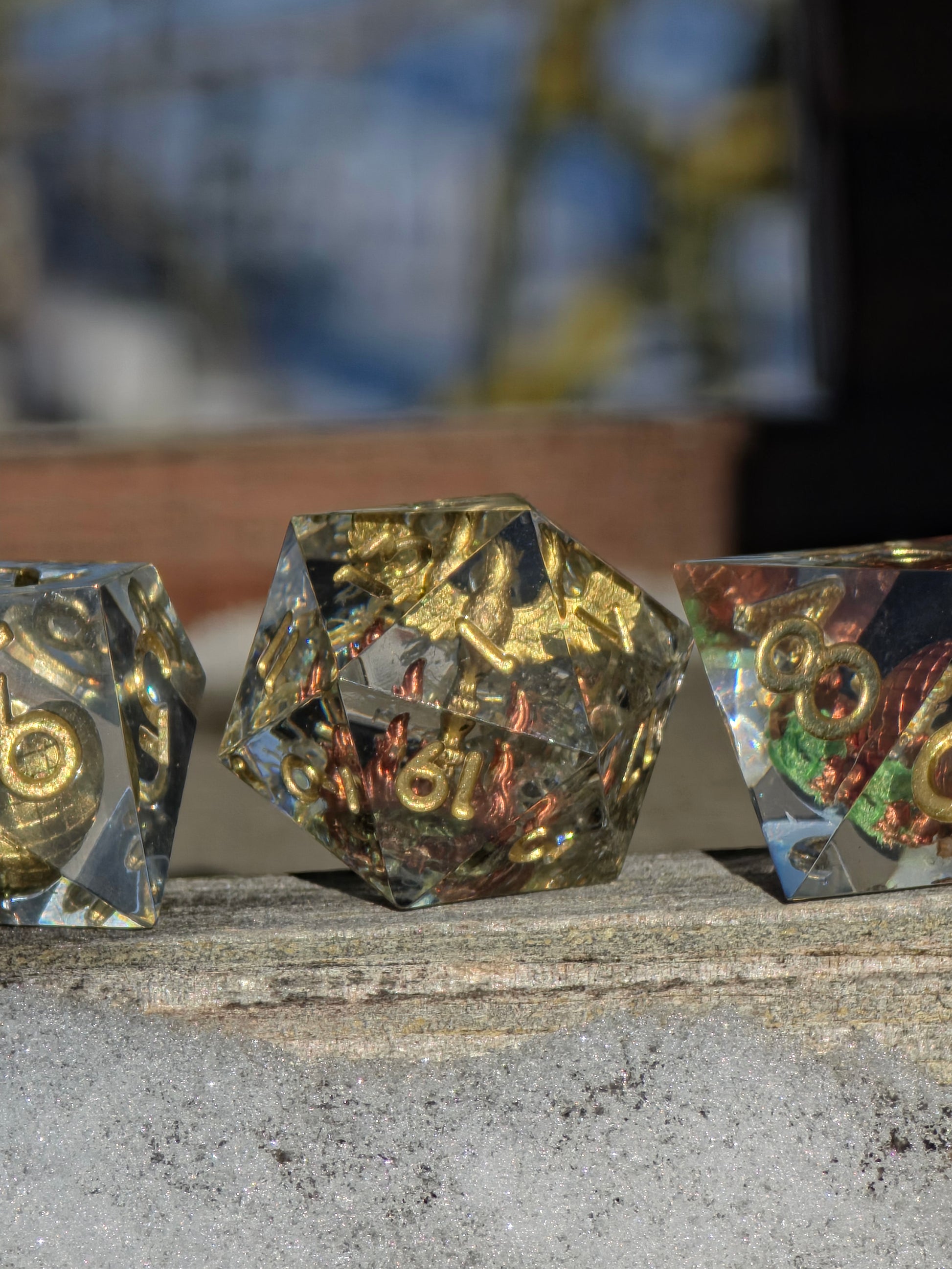 Detailansicht des goldenen Phönix-Dioramas im Würfelset Goldene Wiederkehr aus klarem Resin.  
Close-up of the golden phoenix diorama inside the Goldene Wiederkehr resin dice set.