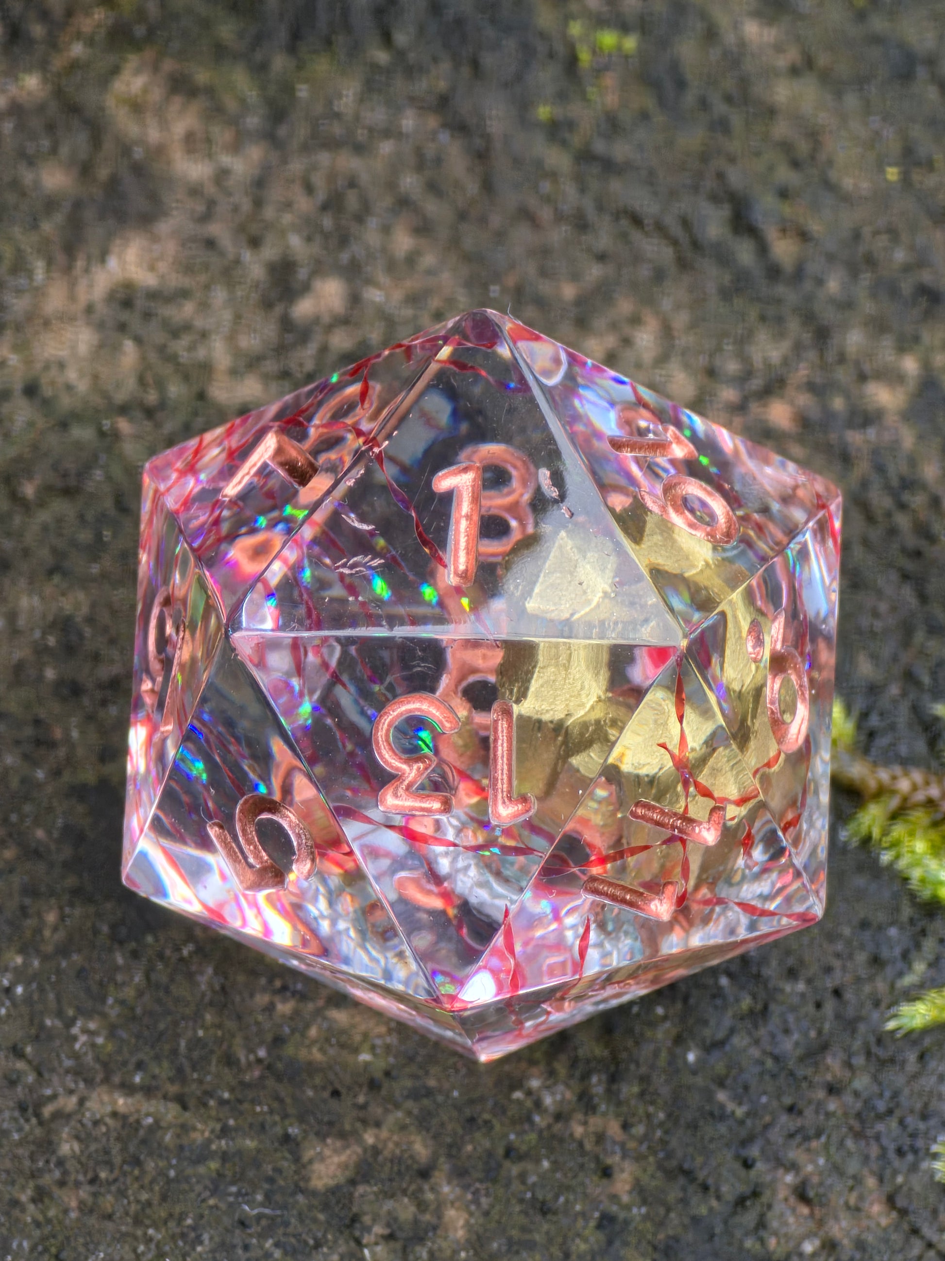 Goldherz des Orakels Kristall D20 in Bewegung zur Darstellung von Lichtreflexionen im Resin.  
Goldherz des Orakels crystal D20 in motion showing resin depth and light reflections.