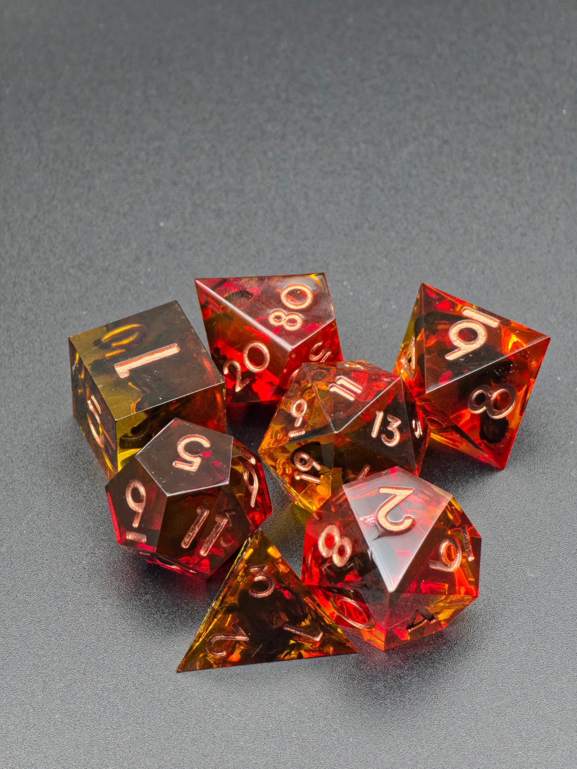 Infernal Amberfall Würfelset im natürlichen Licht mit transparenten Feuer- und Bernsteintönen.  
Infernal Amberfall dice set in natural light showing transparent fire-red and amber hues.