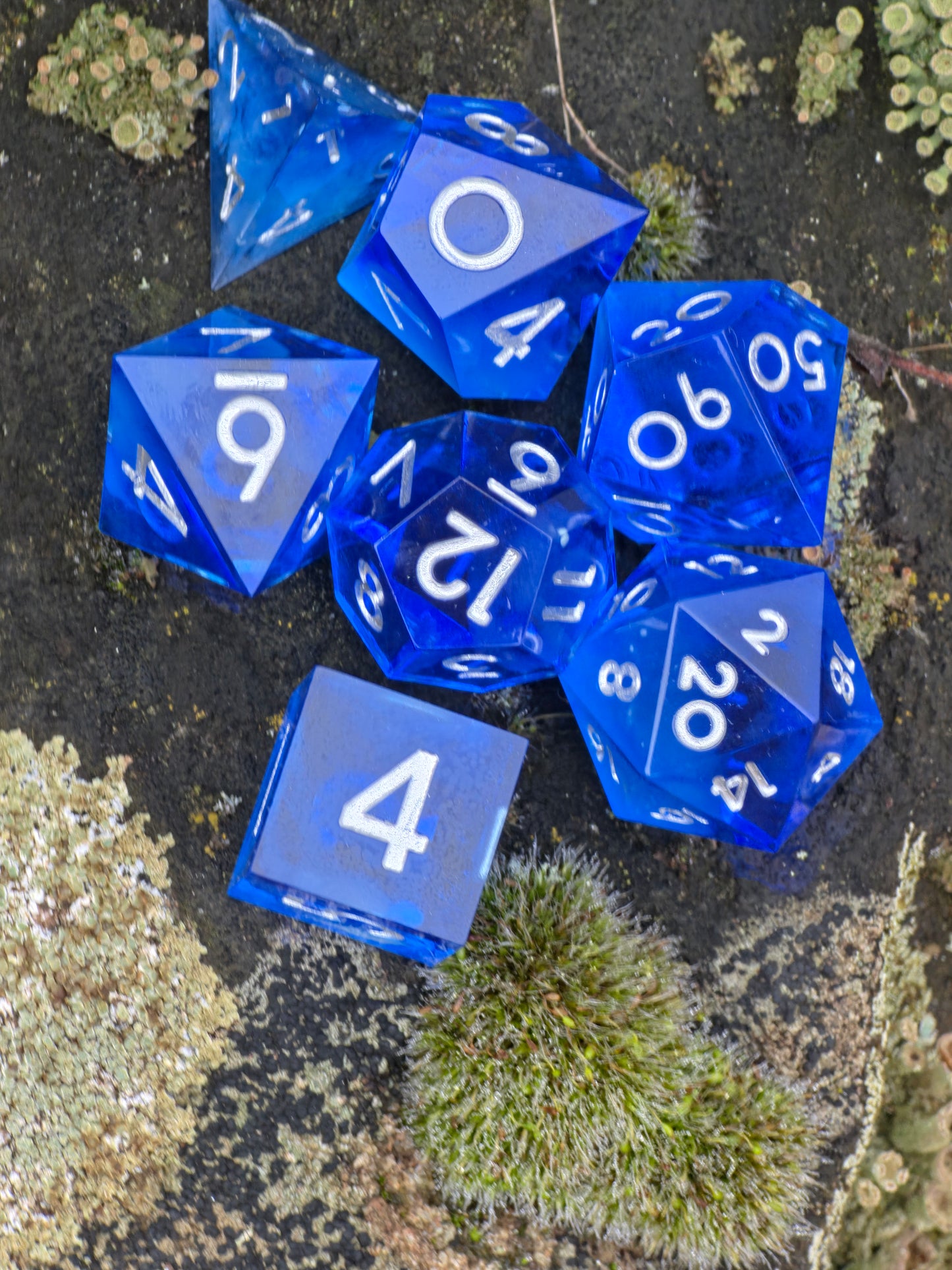 Midnight Nebula Würfelset bei Tageslicht mit klarer Transparenz und intensiven Blautönen.  
Midnight Nebula dice set in daylight showing clear transparency and deep blue tones.
