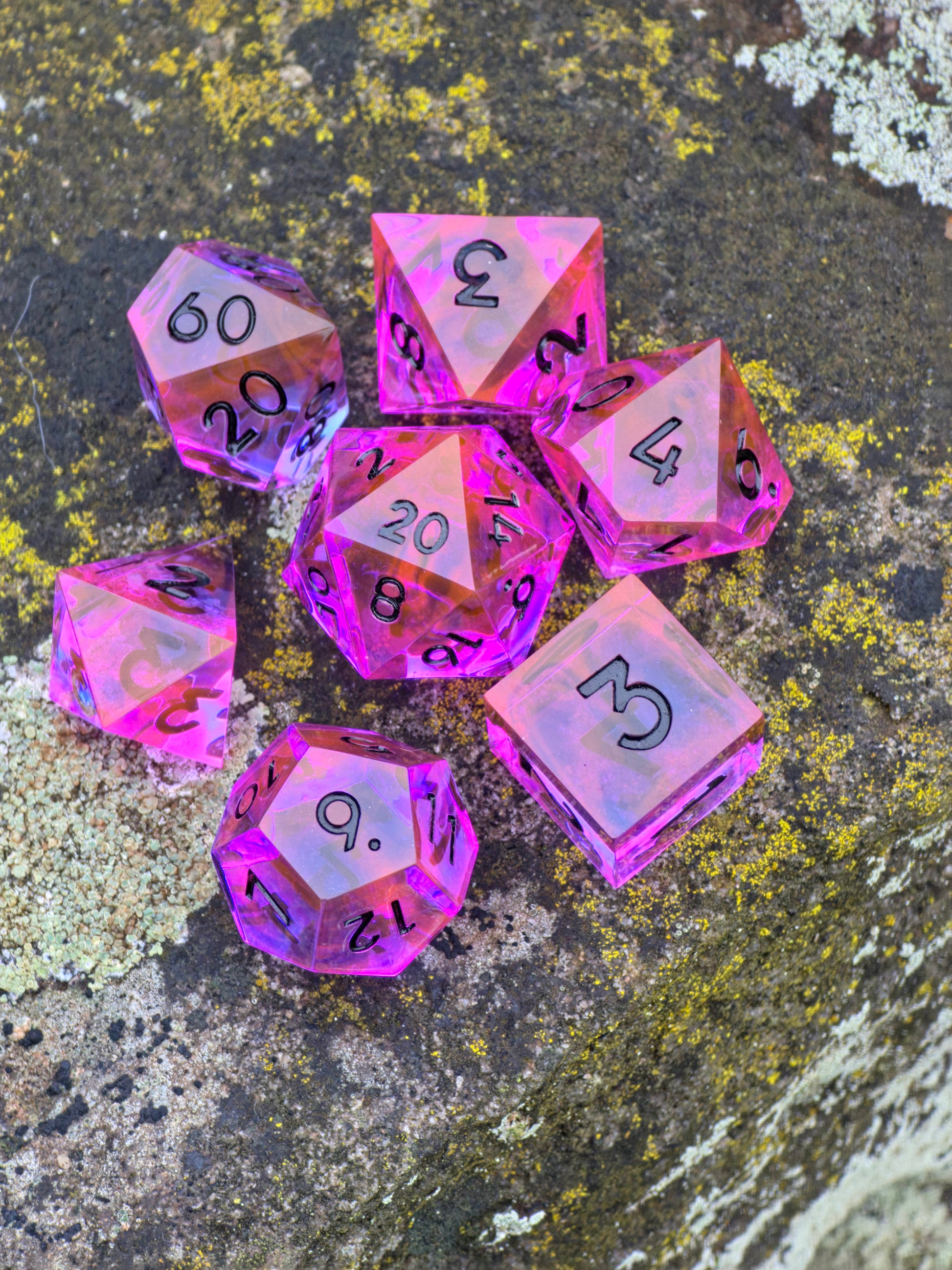 Radiant Ember Würfelset im natürlichen Licht mit glühendem Nebula-Effekt in Pink und Orange.  
Radiant Ember dice set in natural light showing glowing pink and orange nebula tones.