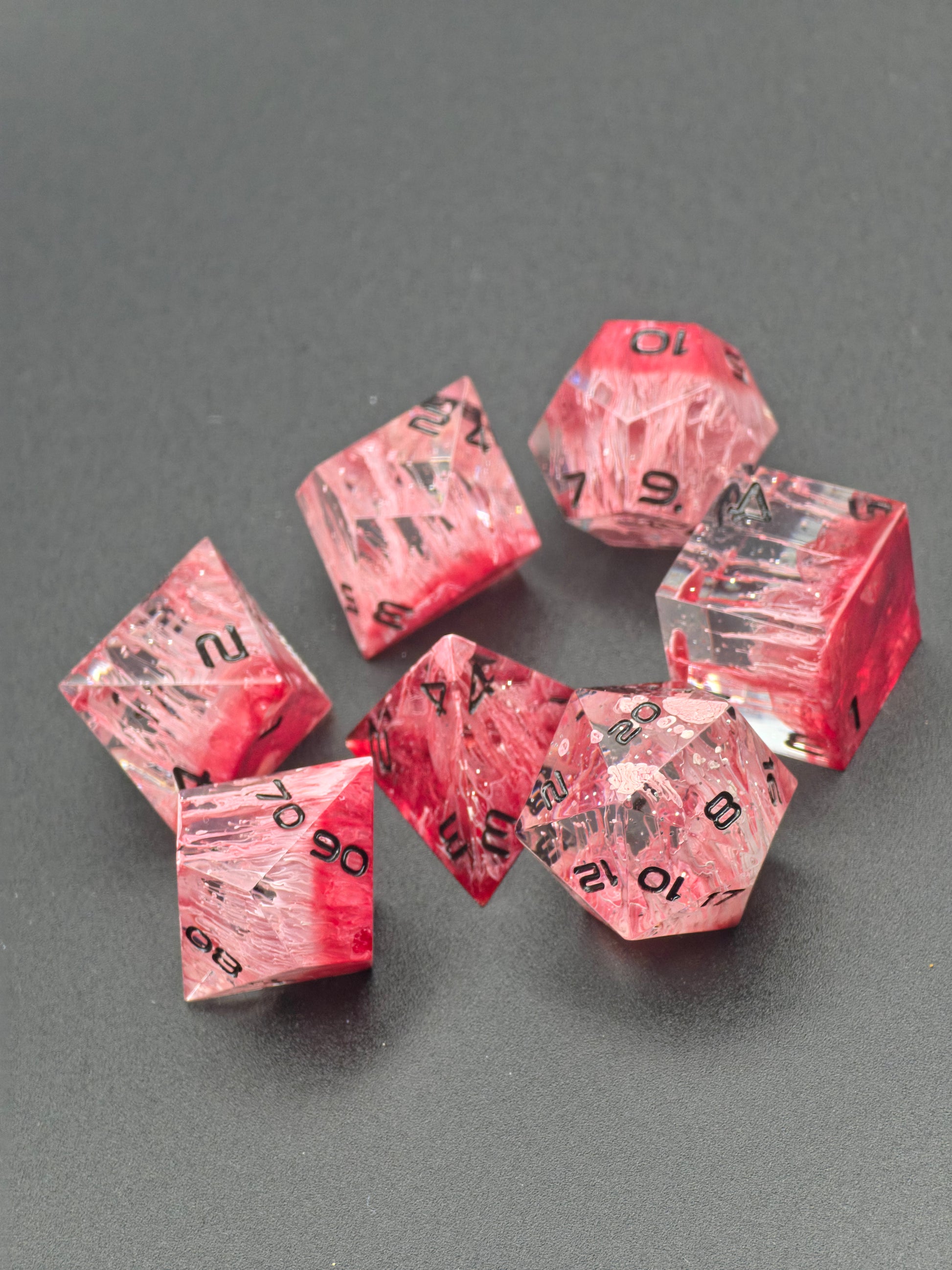 Würfelset Sanguis Veil in Bewegung zur Darstellung von Tiefe, Petri-Fluss und Lichtbrechung.  
Sanguis Veil dice set in motion showing depth, petri flow, and light refraction.