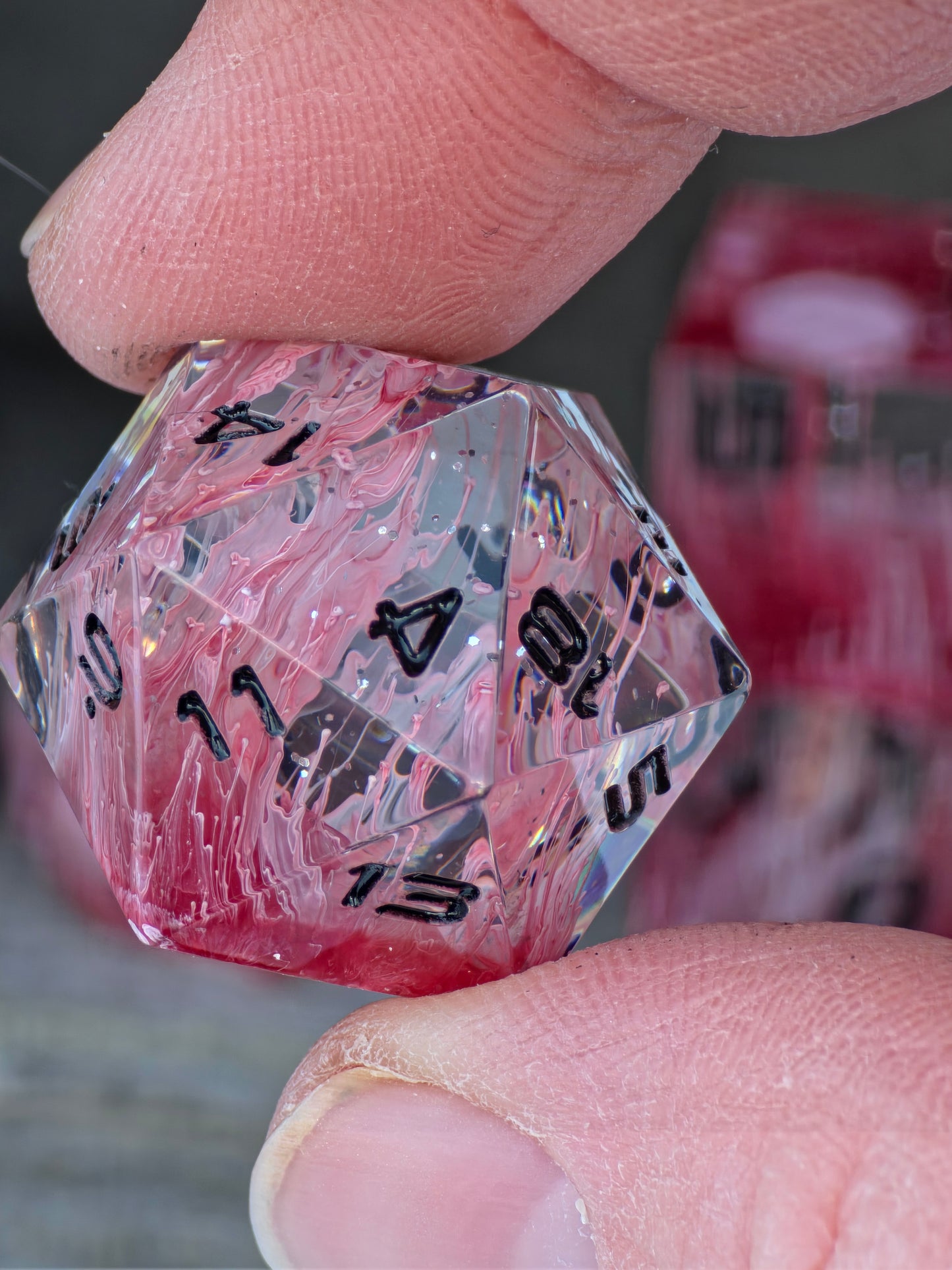 Detailaufnahme der Zahlen und der klaren Resinstruktur des Würfelsets Sanguis Veil.  
Close-up of the numbers and clear resin structure of the Sanguis Veil dice set.