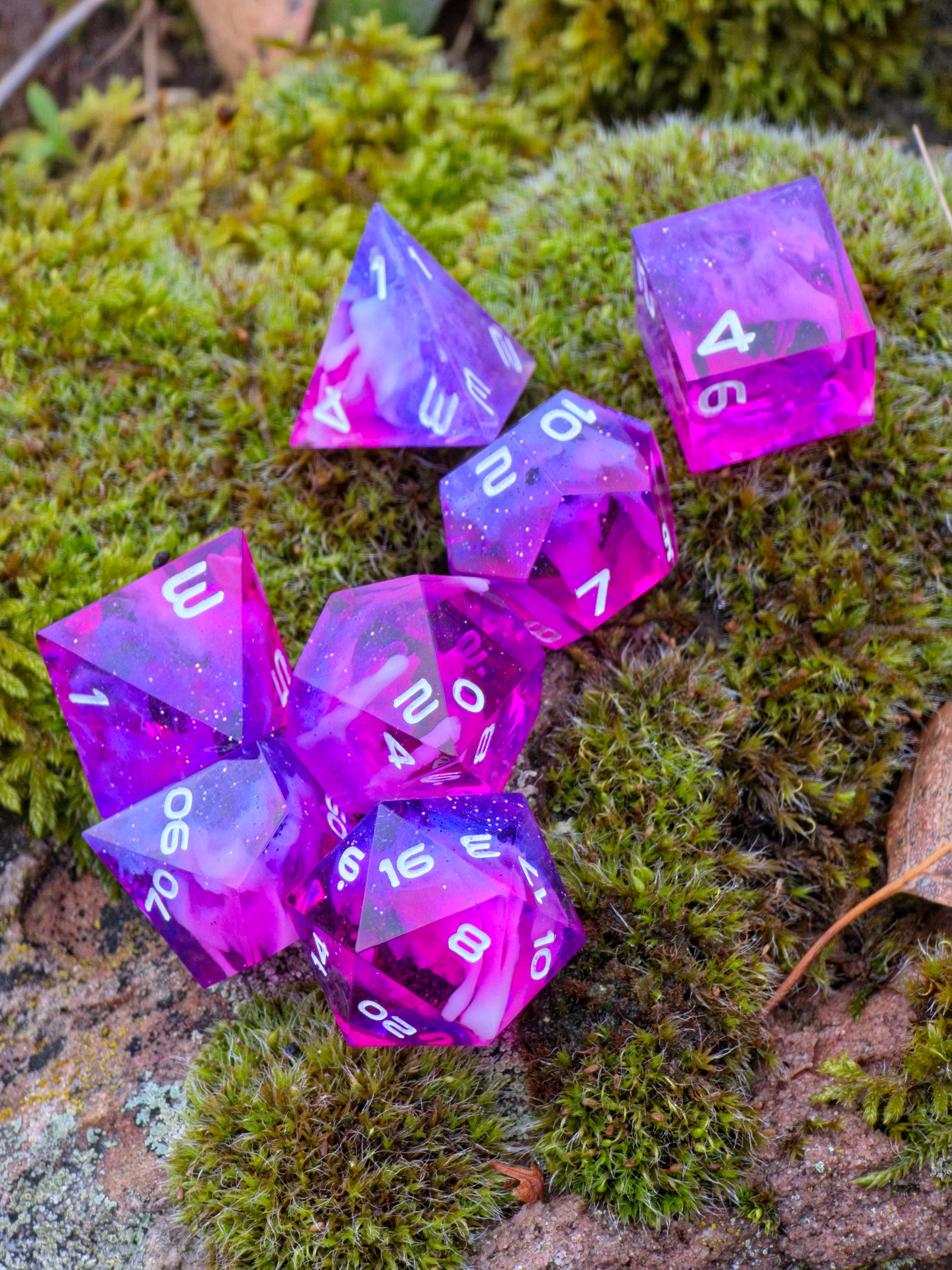 Studioaufnahme des „Starflare Cloud Galaxy“ Würfelsets – klare Kanten, rosa-violette Farbtiefe, Nebula-Glitter.  
Studio shot of the “Starflare Cloud Galaxy” dice set – sharp edges, pink-violet depth, nebula glitter.