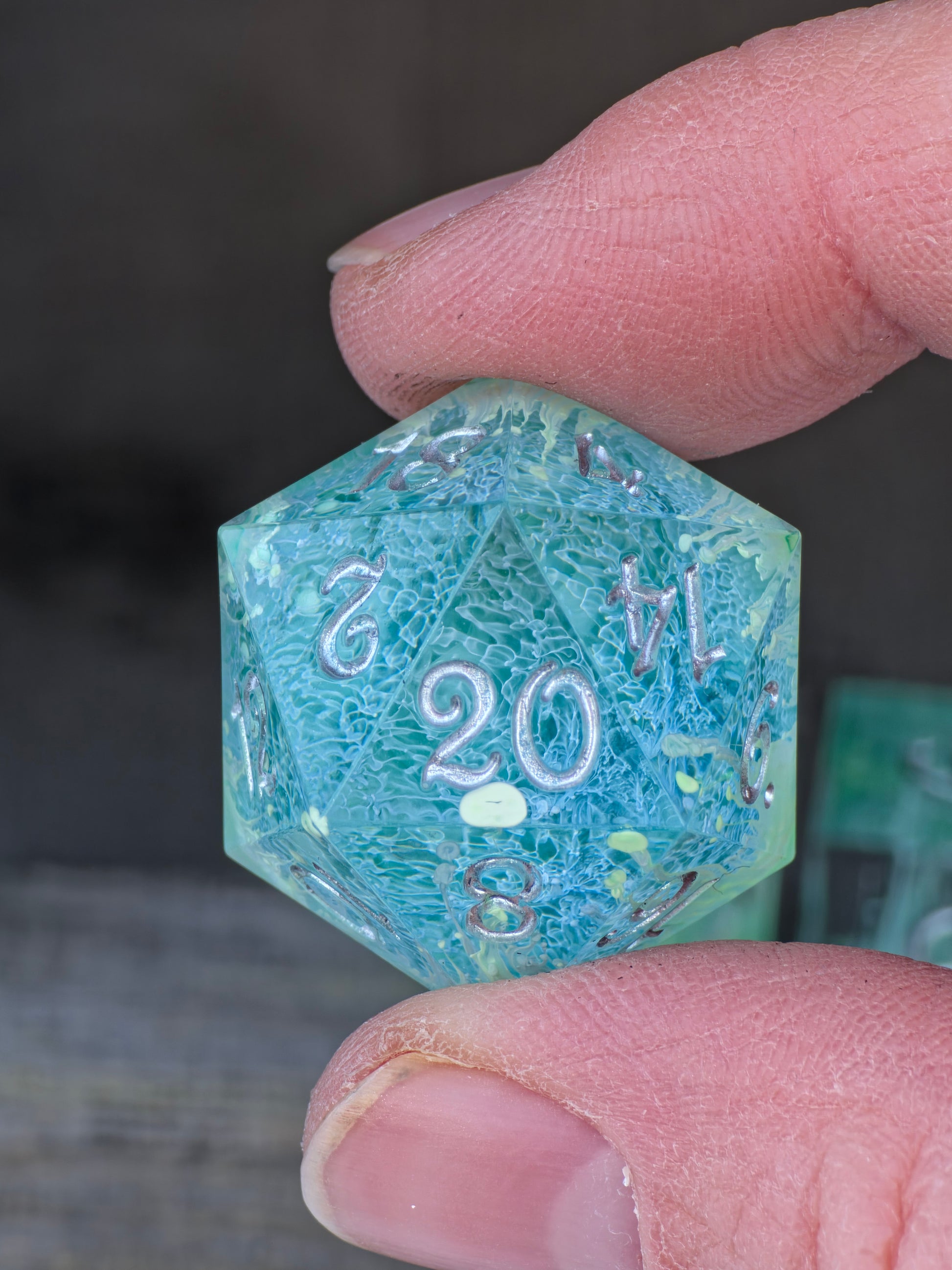 Detailansicht des D20 mit grünem Farbverlauf und Petri-Effekt im Würfelset Verdant Convergence.  
Close-up of the D20 with green color gradient and petri effect in the Verdant Convergence dice set.
