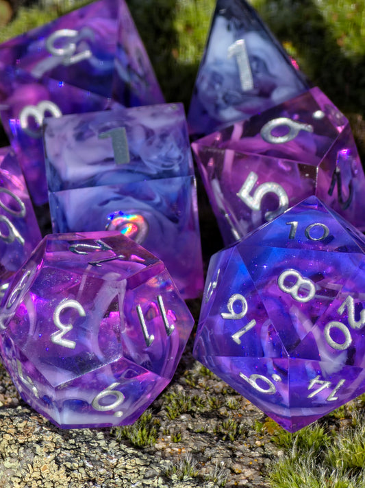 Würfelset „Violet Cloud Nebula“ – gedrehte Perspektive zeigt leuchtende Weißzahlen und Nebelstruktur.  
“Violet Cloud Nebula” dice set – angled view showing bright white numbers and cloud texture.
