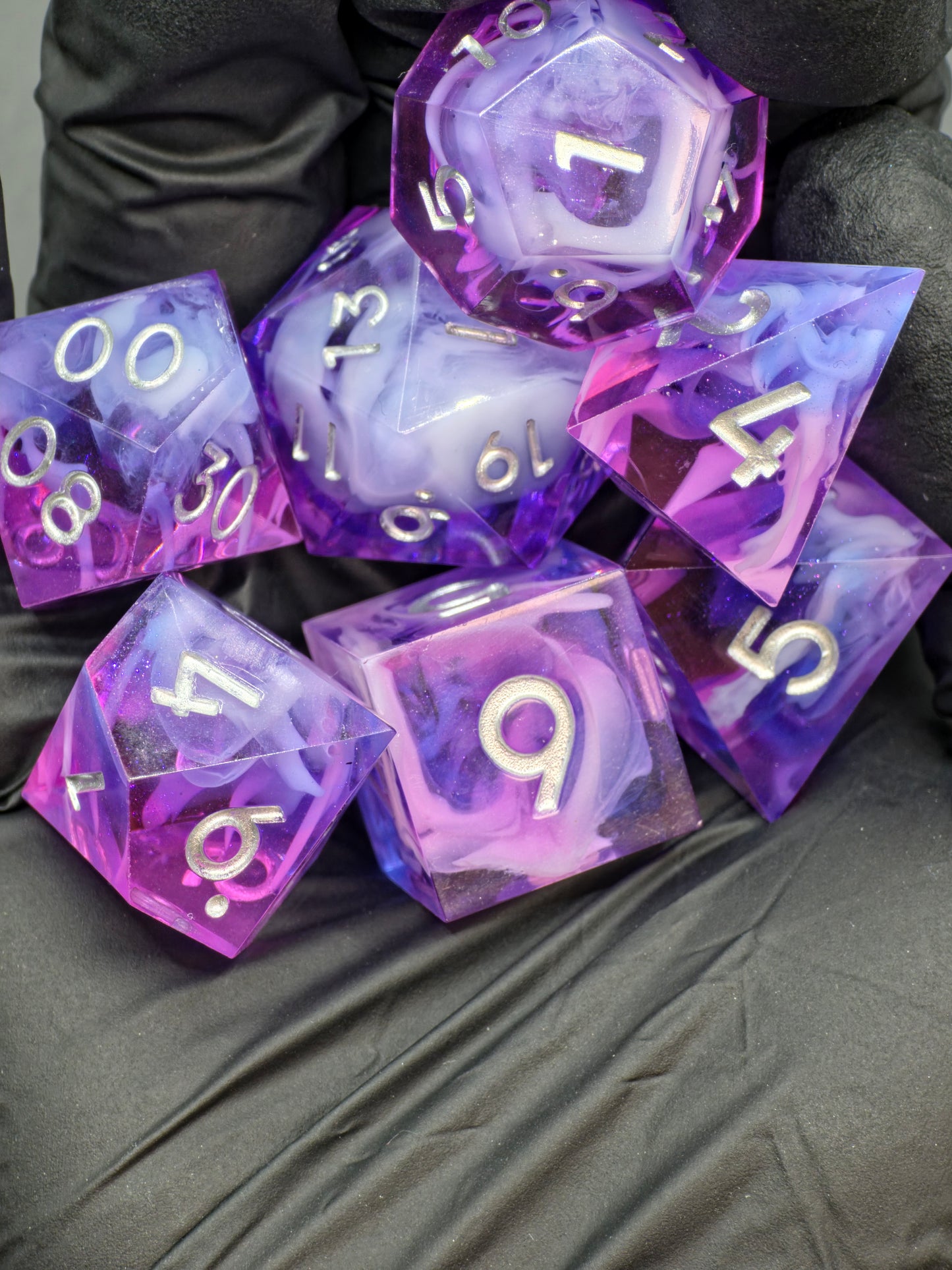 Würfelset „Violet Cloud Nebula“ – gedrehte Perspektive zeigt leuchtende Weißzahlen und Nebelstruktur.  
“Violet Cloud Nebula” dice set – angled view showing bright white numbers and cloud texture.