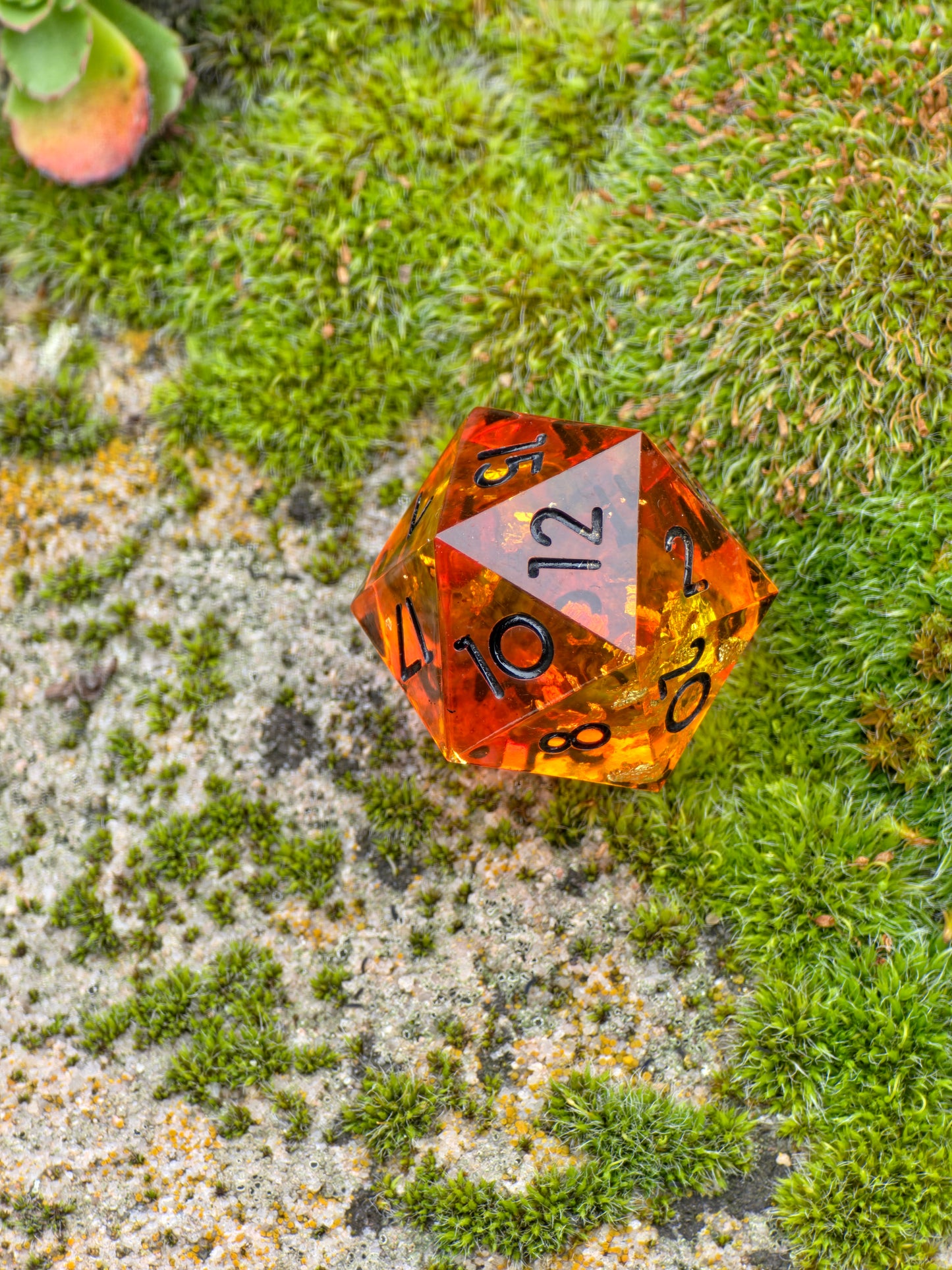 Handgemachter D20 „Amber Bernstein“ – transparenter Würfel in Gold und Orange mit Blattgold.  
Handmade D20 “Amber Bernstein” – transparent gold and orange die with gold leaf inclusions.