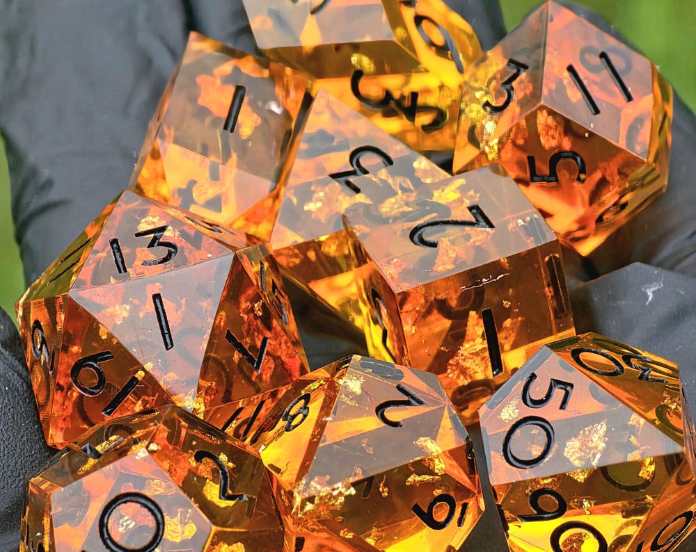 „Amber Bernstein“ in der Hand – warm leuchtende Würfel mit goldenen Reflexen im Sonnenlicht.  
“Amber Bernstein” held in hand – warmly glowing dice with golden reflections in sunlight.