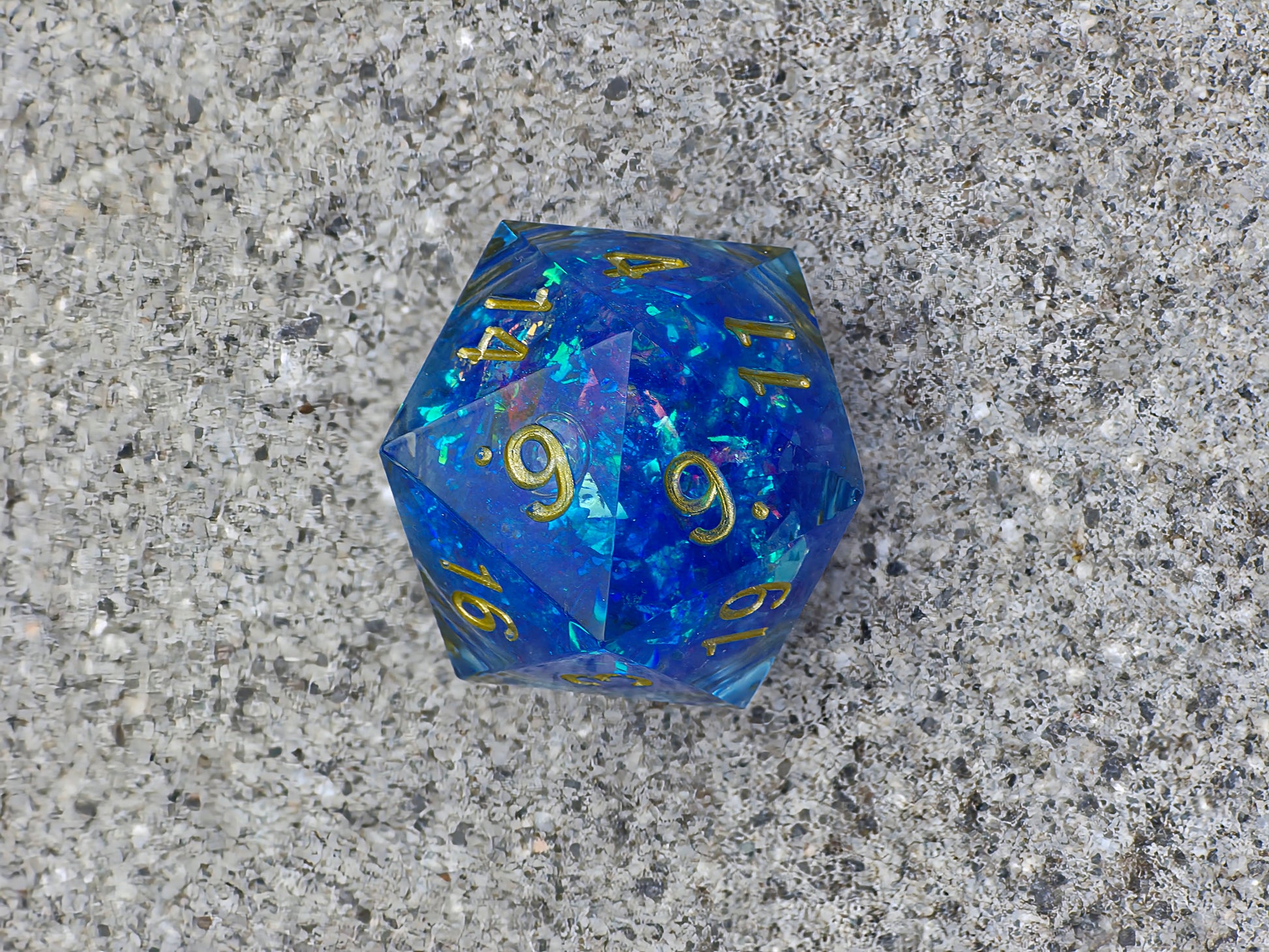 Handgemachter D20 „Arcane Energy“ – großer Liquid Core Würfel in tiefem Blau mit goldenem Schimmer.  
Handmade D20 “Arcane Energy” – large liquid core die in deep blue with golden shimmer.