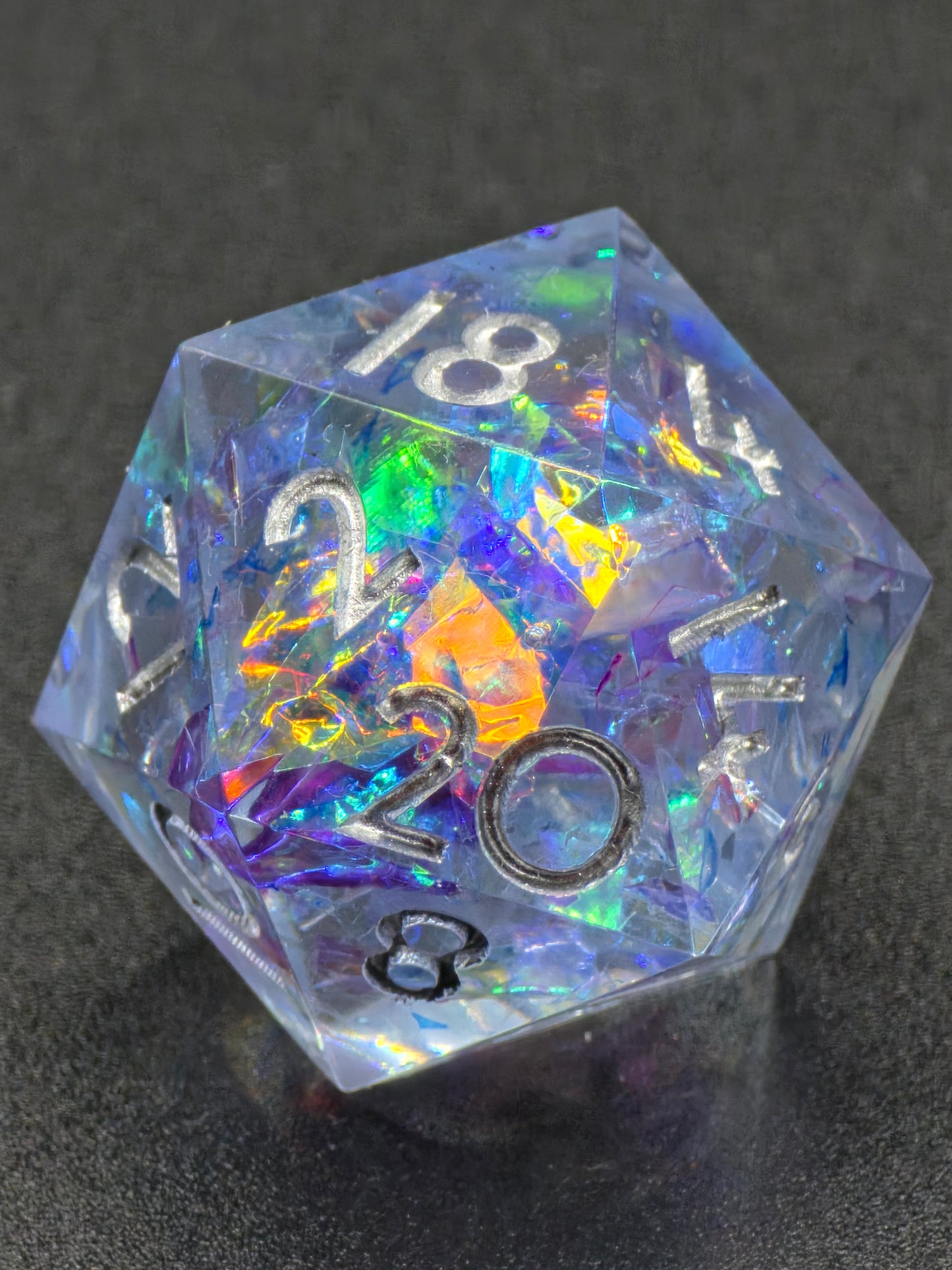 Handgemachter polyedrischer D20 „Aurora Crystal“ – transparenter Resinwürfel mit irisierendem Opalschimmer.  
Handmade polyhedral D20 “Aurora Crystal” – transparent resin die with iridescent opal shimmer.