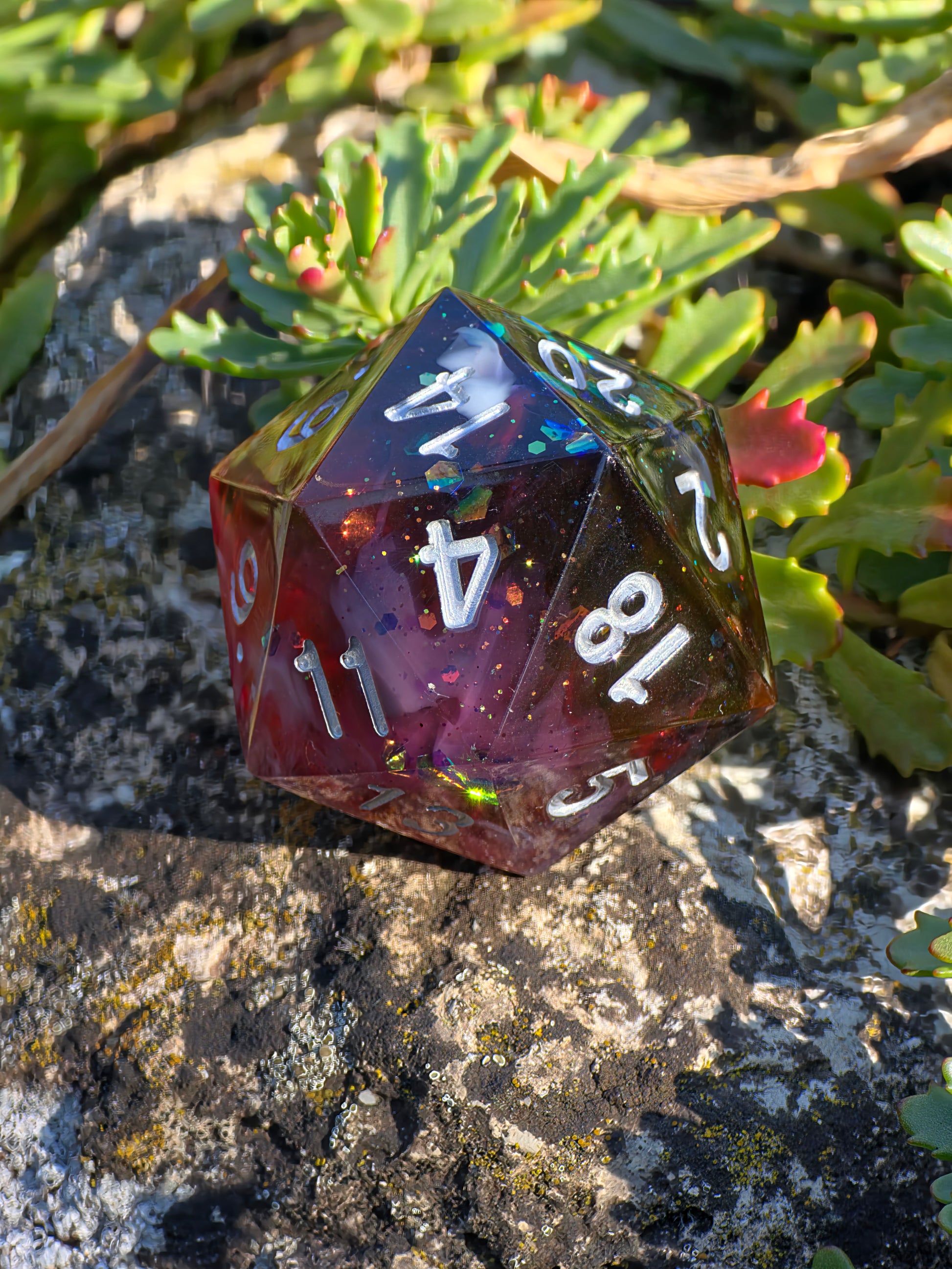 „Blood & Mist“ in der Hand – tiefer Rotton mit kontrastierenden schwarzen Akzenten und weißem Schimmer.  
“Blood & Mist” held in hand – deep red tones with contrasting black accents and white shimmer.