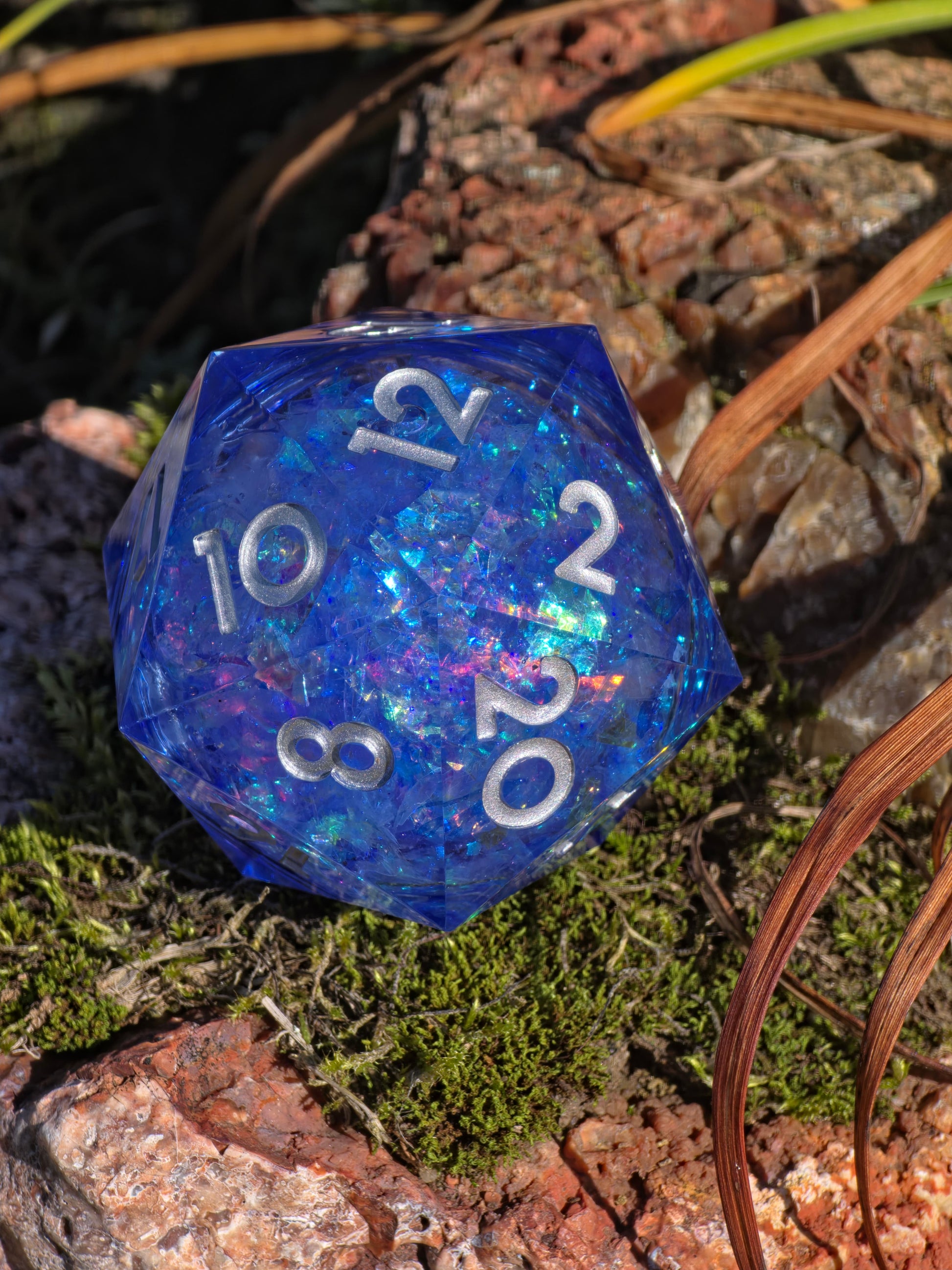 Handgemachter XL D20 „Blue Opal Liquid Core“ – blauer Würfel mit Flüssigkern und Opaleffekt.  
Handmade XL D20 “Blue Opal Liquid Core” – blue resin die with liquid core and opal effect.
