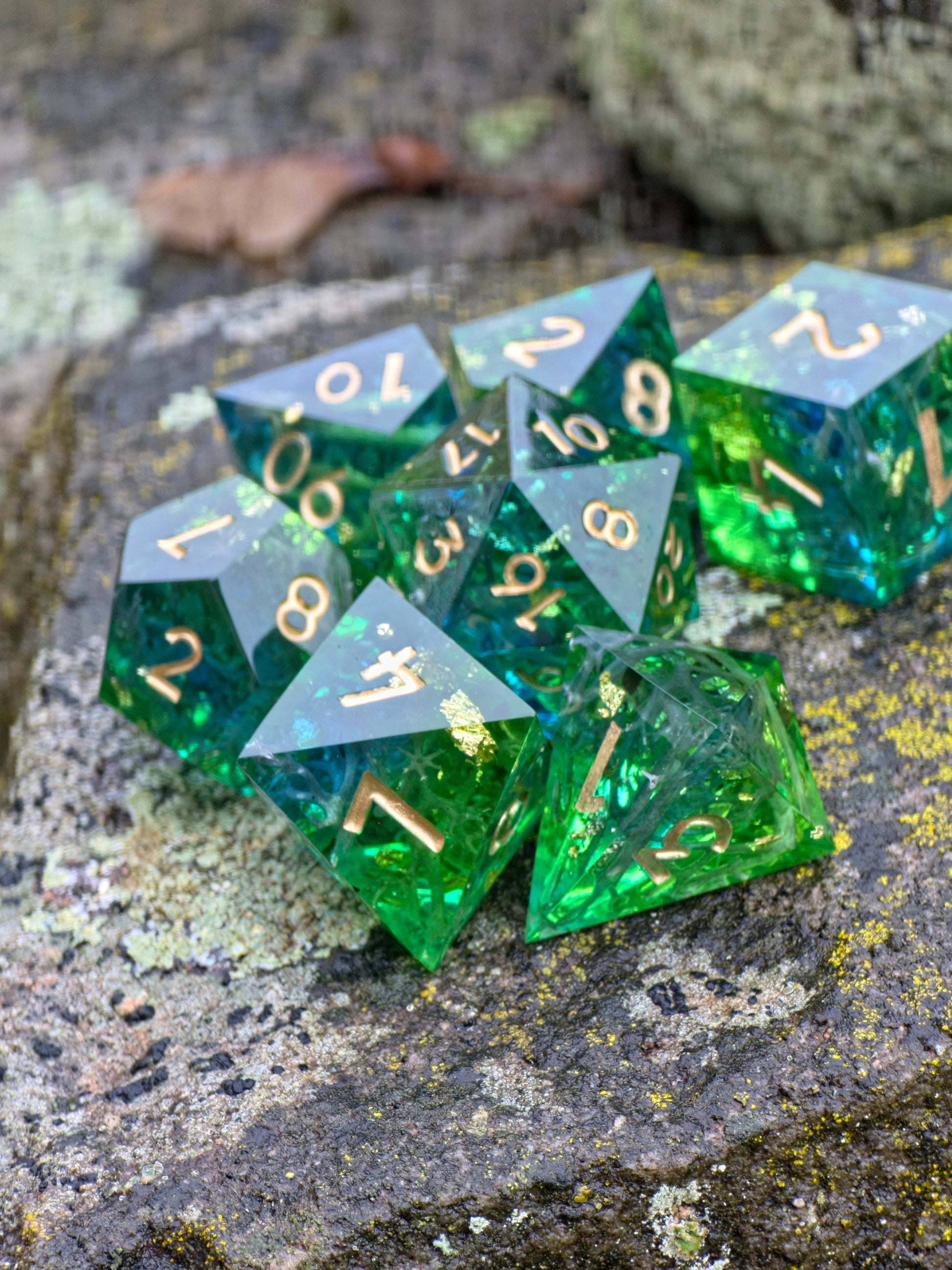 Detailaufnahme der „Emerald Grove“ Würfel – goldene Flocken, glitzernde Harzschichten und Moosdetails.  
Close-up of the “Emerald Grove” dice – golden flakes, shimmering resin layers and moss-like details.