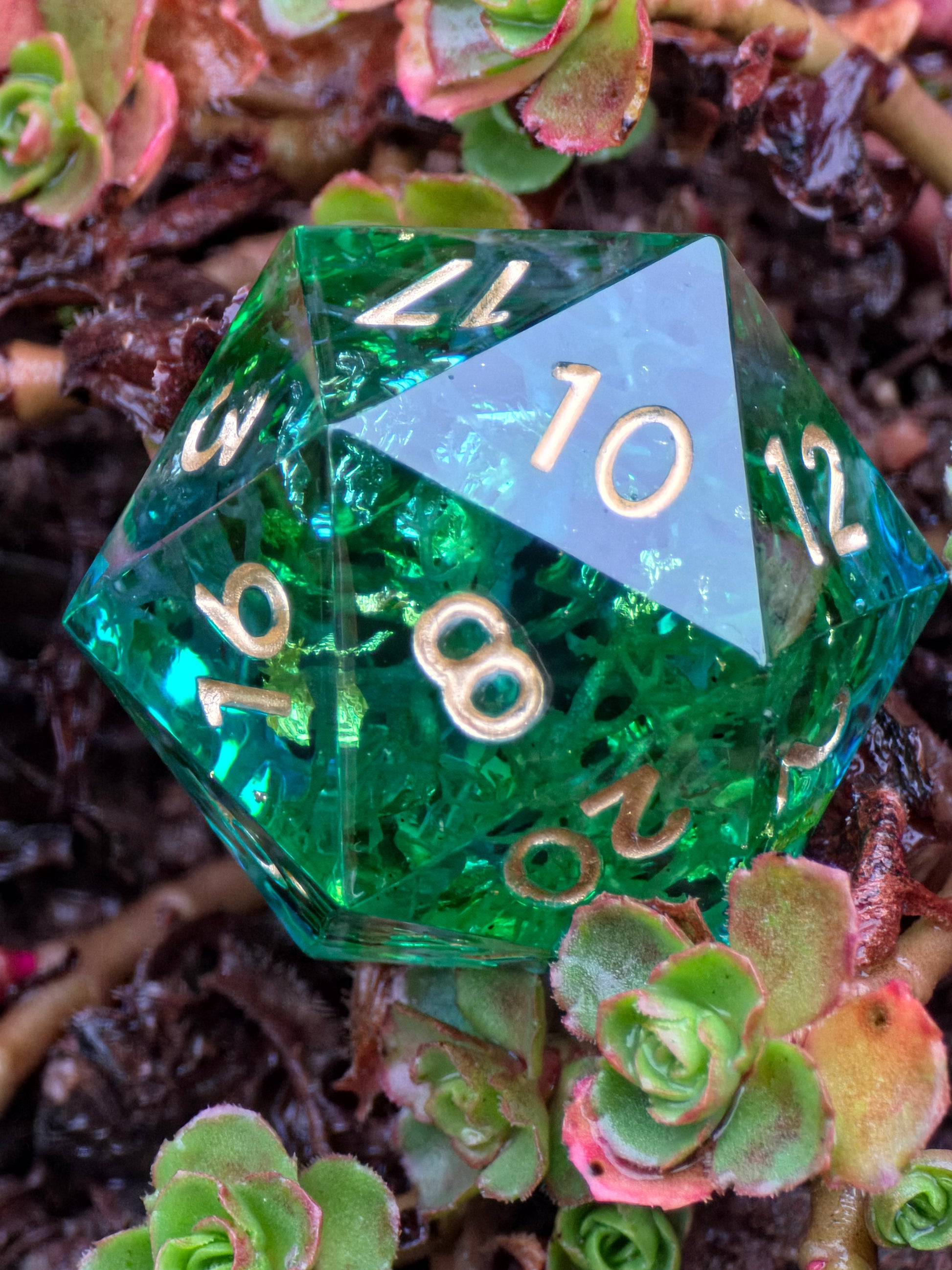Handgemachtes polyedrisches Würfelset „Emerald Grove“ aus smaragdgrünem Resin mit goldenen Flocken und Moosstruktur – inspiriert vom alten Wald.  
Handmade polyhedral dice set “Emerald Grove” in emerald green resin with golden flakes and moss texture – inspired by the ancient forest.