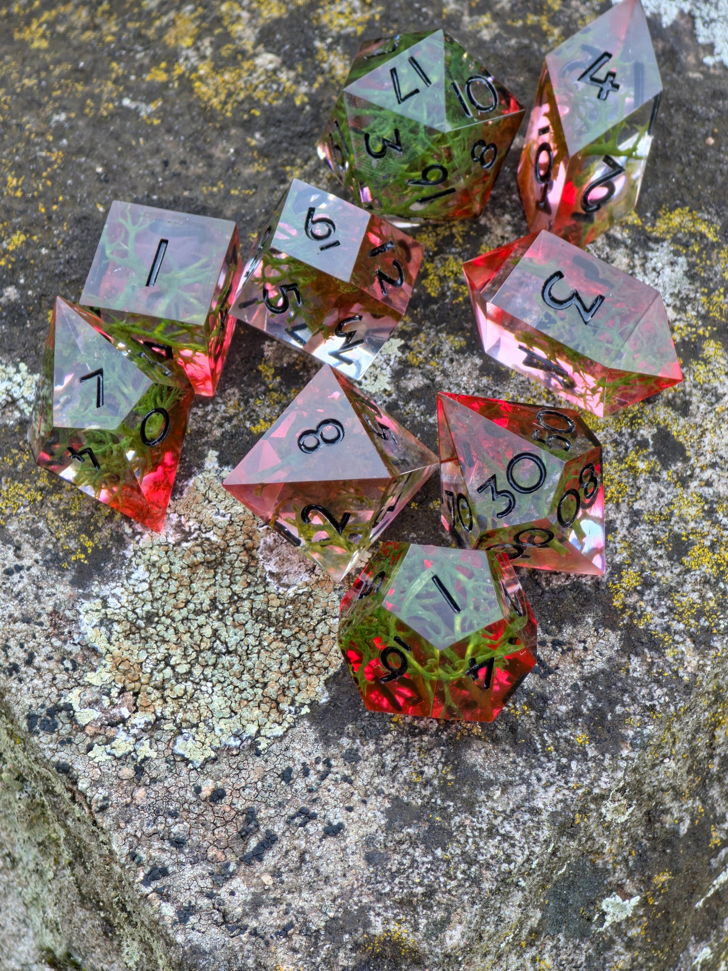 „Forest Ember“ Würfelset auf natürlichem Hintergrund – rotes Licht trifft auf grünes Moos, wie Waldfunken im Abendlicht.  
“Forest Ember” dice set on natural background – red light meets green moss, like forest embers in evening glow.