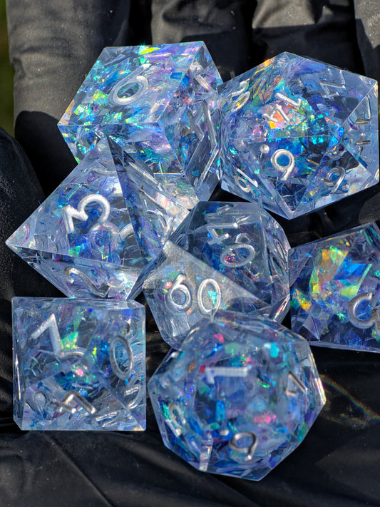 Handgemachtes polyedrisches Würfelset „Frozen Aurora“ aus klarem Resin mit eisblauem Opal-Effekt – inspiriert vom gefrorenen Nordlicht.  
Handmade polyhedral dice set “Frozen Aurora” in clear resin with icy blue opal effect – inspired by the frozen northern lights.