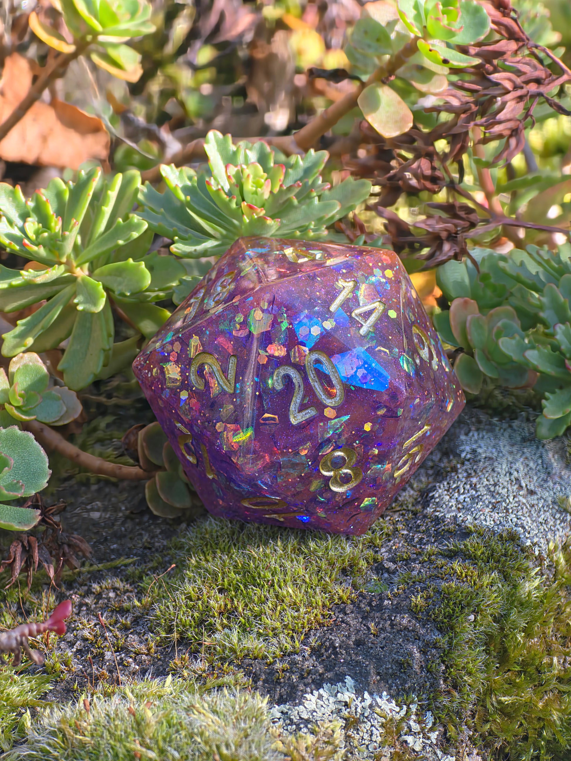 „Galaxy Blossom“ in der Hand – funkelndes Violett-Rosa mit goldener Gravur.  
“Galaxy Blossom” held in hand – shimmering violet-pink with golden engraving.