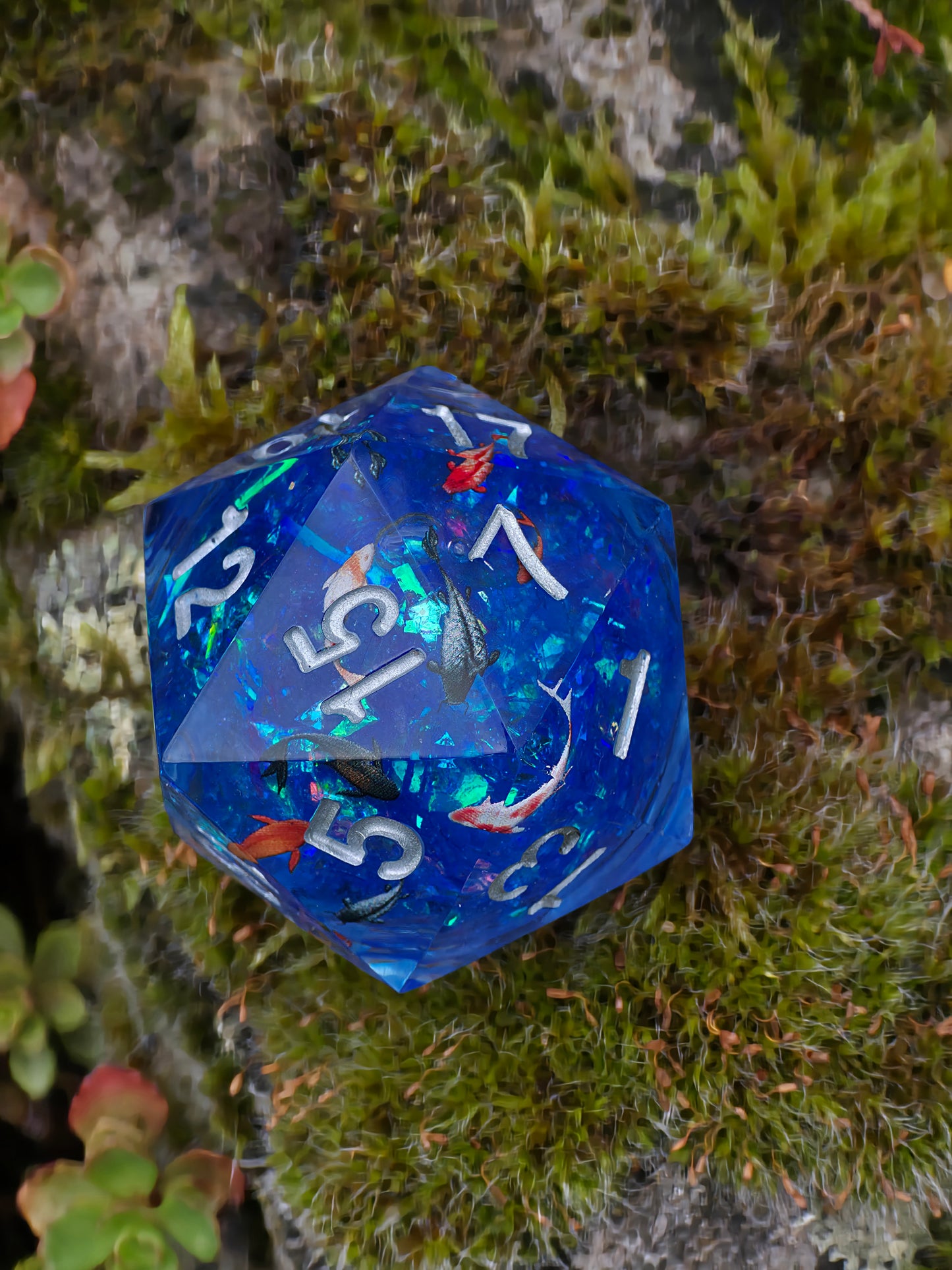 Detailaufnahme des „Koi Pond“ Würfels – schimmernde Wasseroptik und realistische Miniaturfische im Inneren.  
Close-up of the “Koi Pond” die – shimmering water effect and realistic miniature koi fish inside.