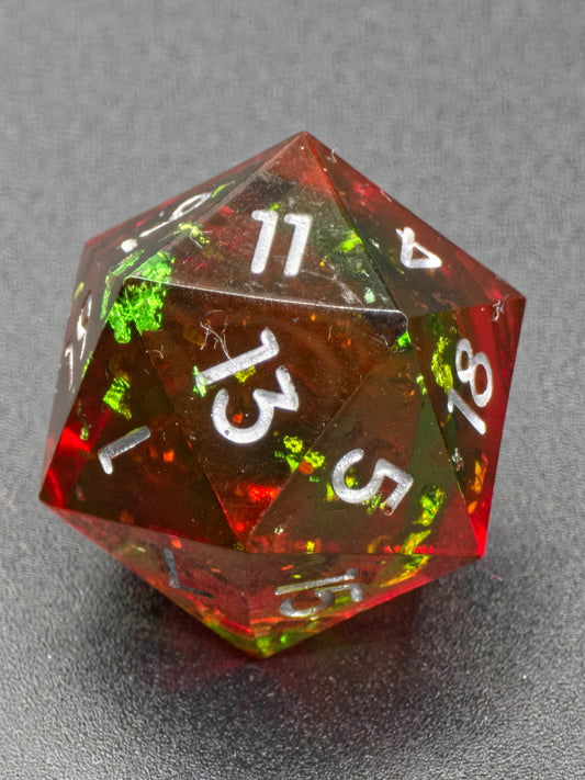 Handgemachter polyedrischer D20 „Lava Effekt“ – roter und grüner Resinwürfel mit transparenter Magmastruktur.  
Handmade polyhedral D20 “Lava Effect” – red and green resin die with transparent magma structure.