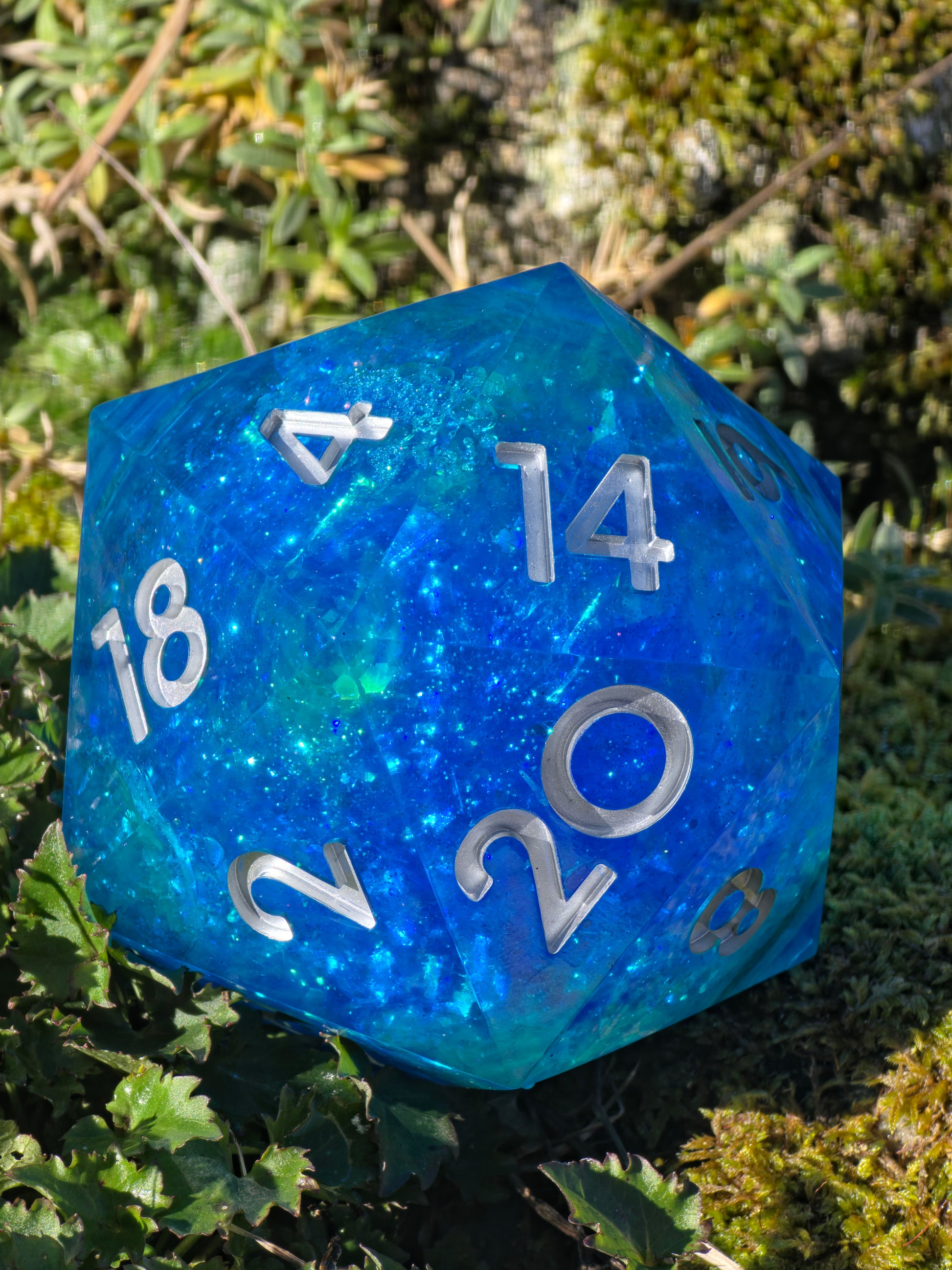 Handgemachter XXL D20 „Ocean Blue Liquid Core“ – transparenter Würfel in Türkisblau mit flüssigem Kern.  
Handmade XXL D20 “Ocean Blue Liquid Core” – transparent turquoise-blue die with moving liquid core.