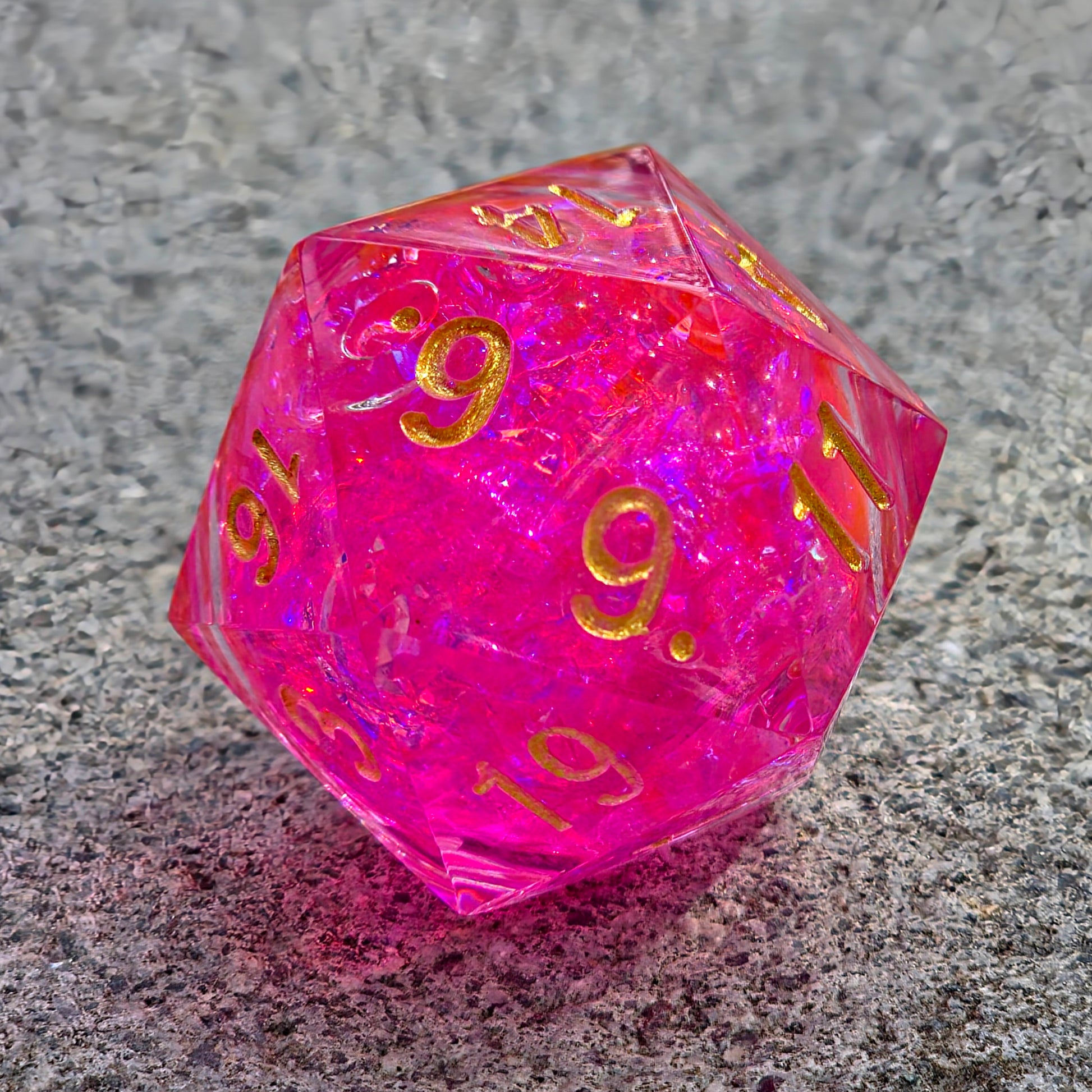 Detailaufnahme des „Pink Aurora“ – schimmernde Flakes, flüssiger Kern und goldene Reflexe.  
Close-up of “Pink Aurora” – shimmering flakes, liquid core, and golden reflections.