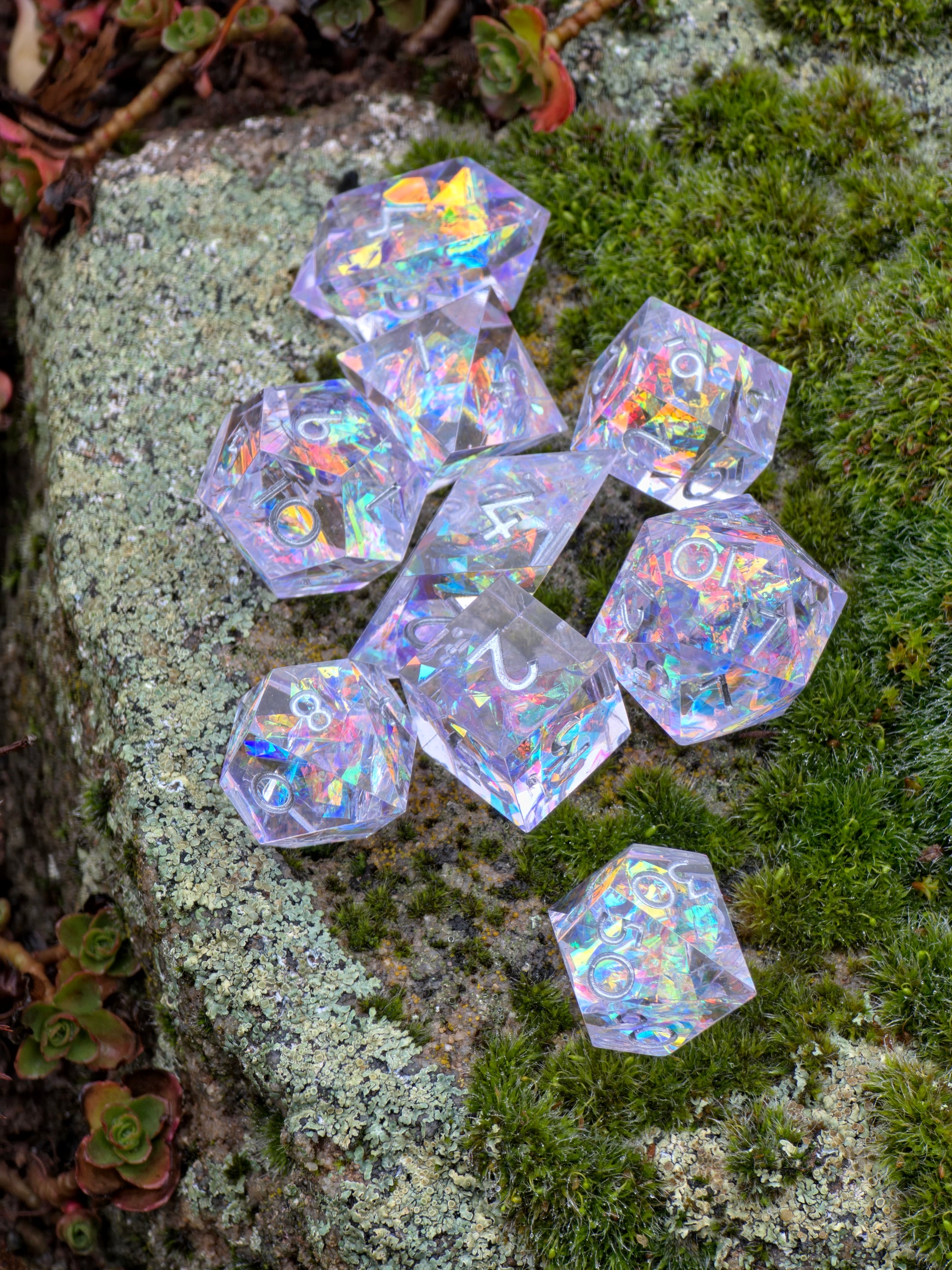 „Prism Aurora“ Würfelset auf Moos fotografiert – zeigt den irisierenden Glanz und transparente Tiefe des Harzes.  
“Prism Aurora” dice set photographed on moss – showing the iridescent shine and translucent depth of the resin.